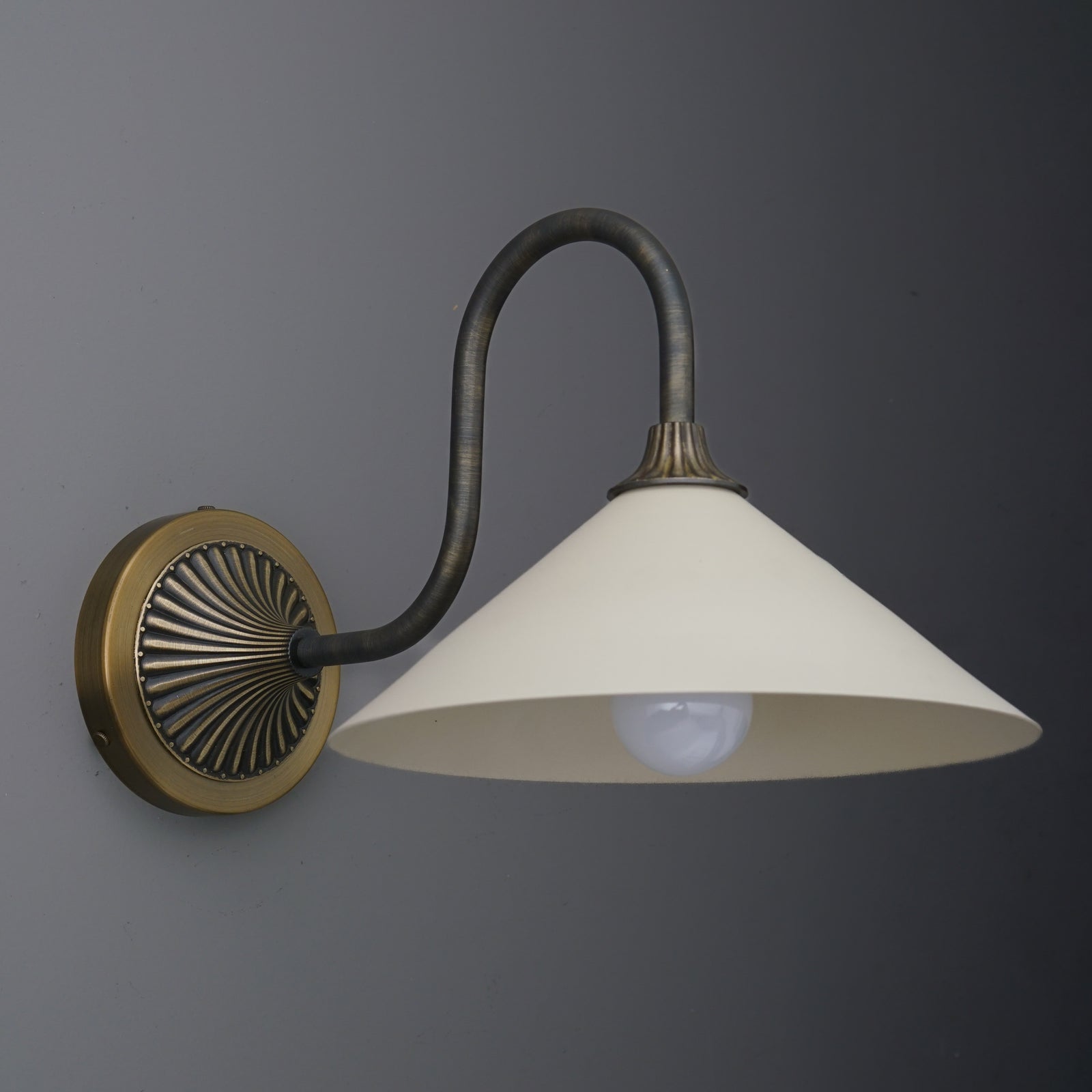 Wall sconce with antique brass finish, curved arm, and white conical glass shade over bulb. - SCONCE MODEL NO. 1031