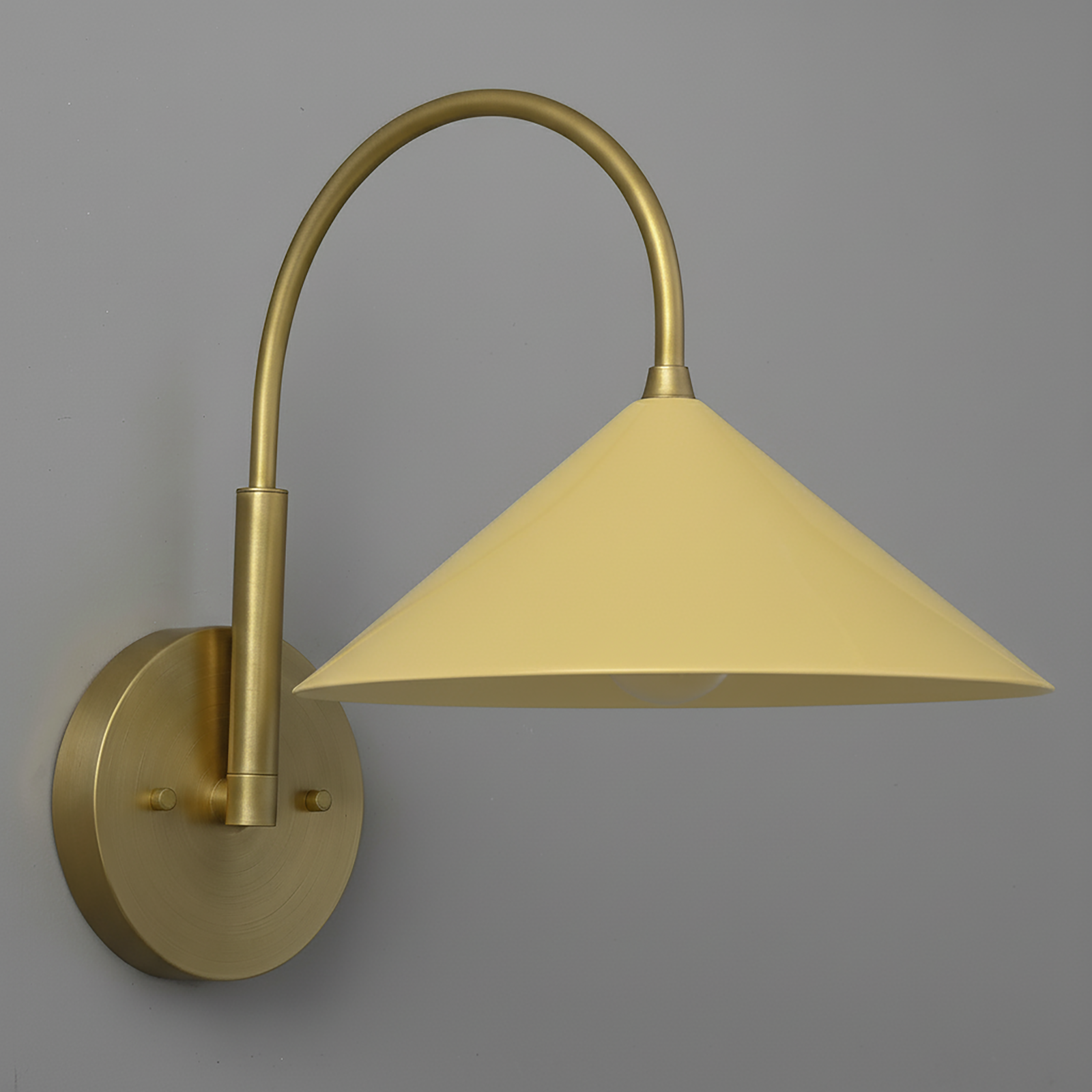Antique brass sconce with curved arm and yellow conical metal shade against gray background. - Sconce Model No. 1583