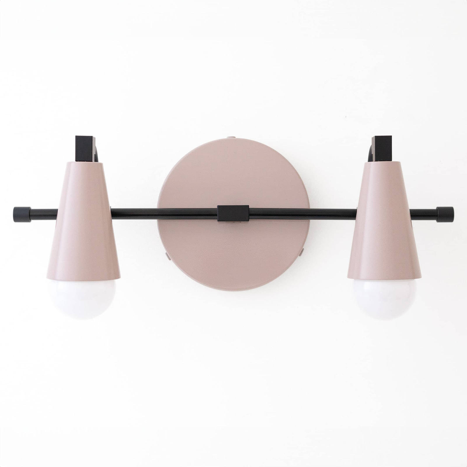 Wall-mounted vanity light with two muted pink cone-shaped shades and white round bulbs on a black horizontal rod. - VANITY LIGHT MODEL NO. 1229