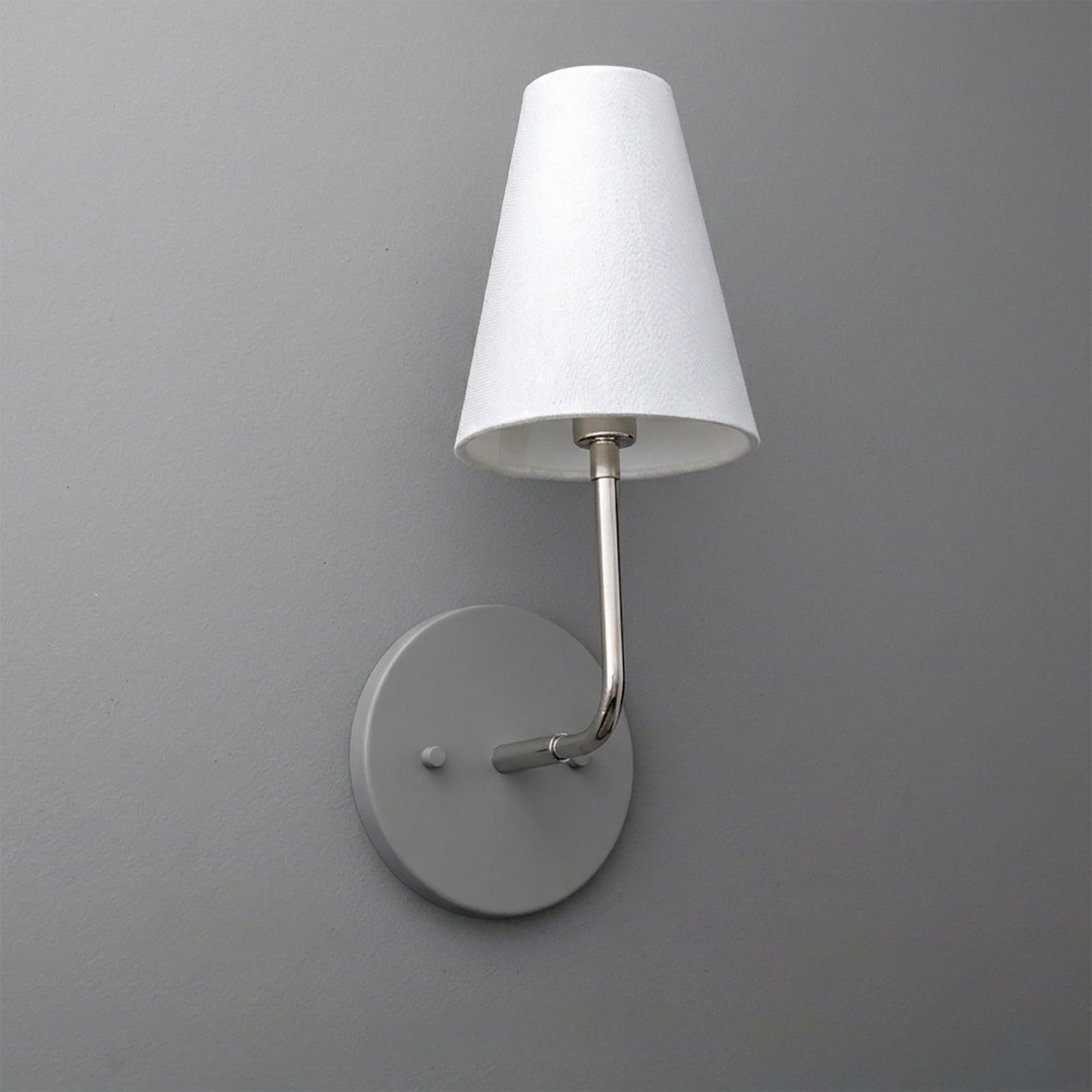 Metal wall sconce with round base and curved arm holding a white fabric tapered lampshade. - SCONCE MODEL NO. 3928
