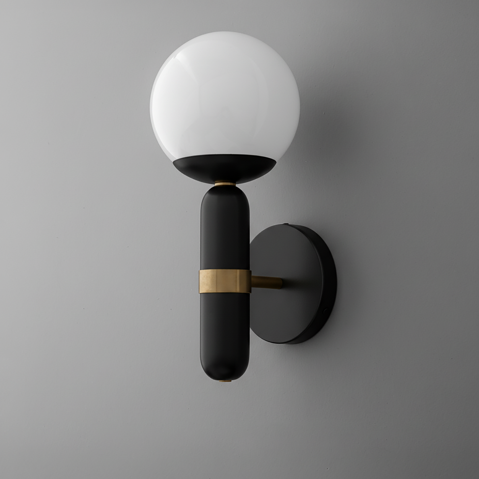 Wall sconce with round white glass shade and black cylindrical base featuring a brass accent band. - SCONCE MODEL NO. 4786