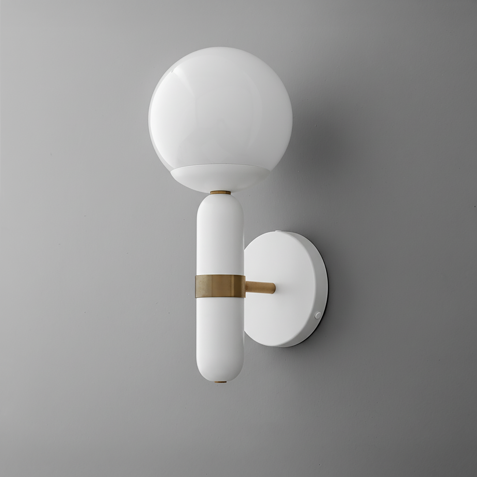 Wall sconce with round white glass globe and white cylindrical base with brass accent on gray wall. - SCONCE MODEL NO. 4786