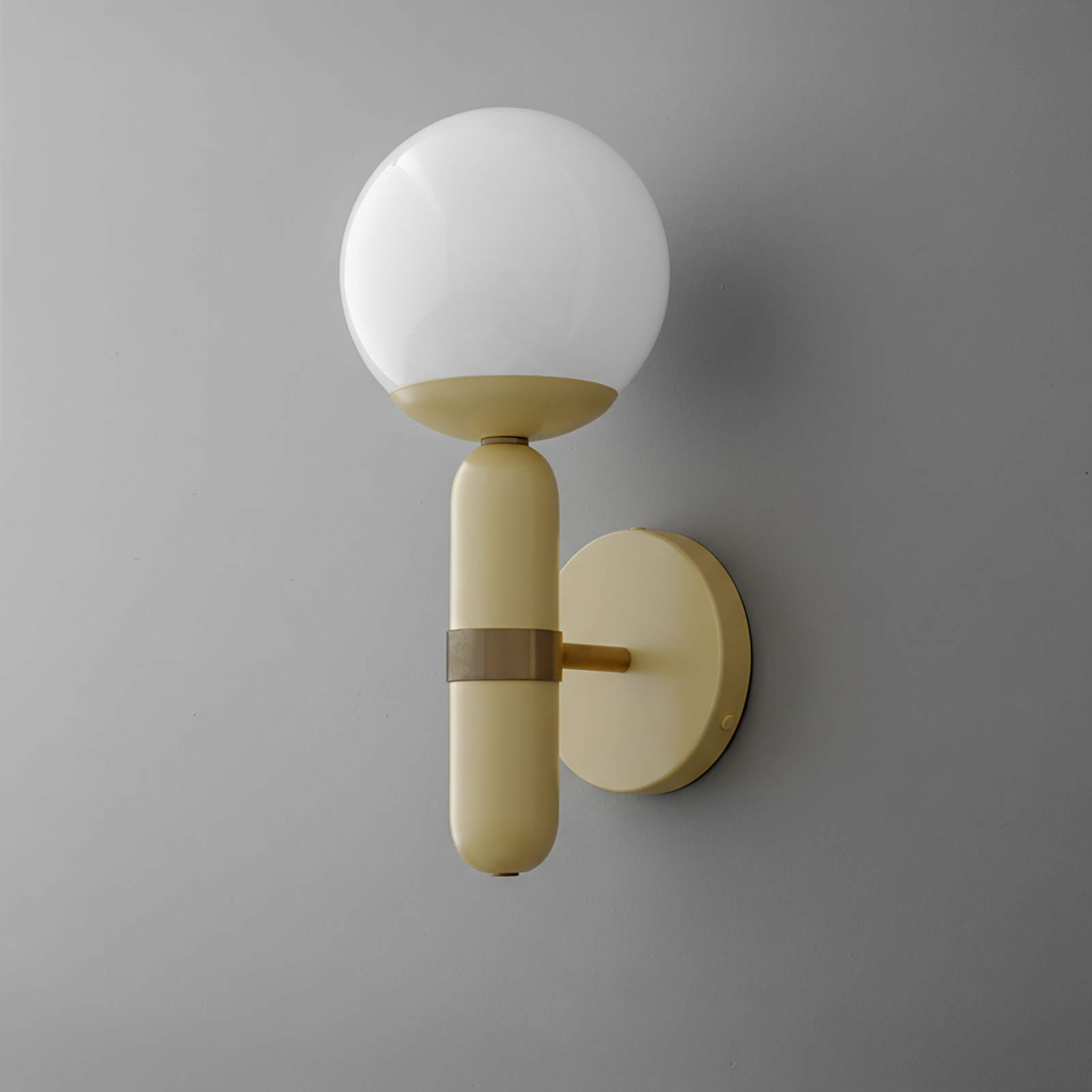 Wall sconce with round white glass globe and vertical cream brass base on gray wall. - SCONCE MODEL NO. 4786