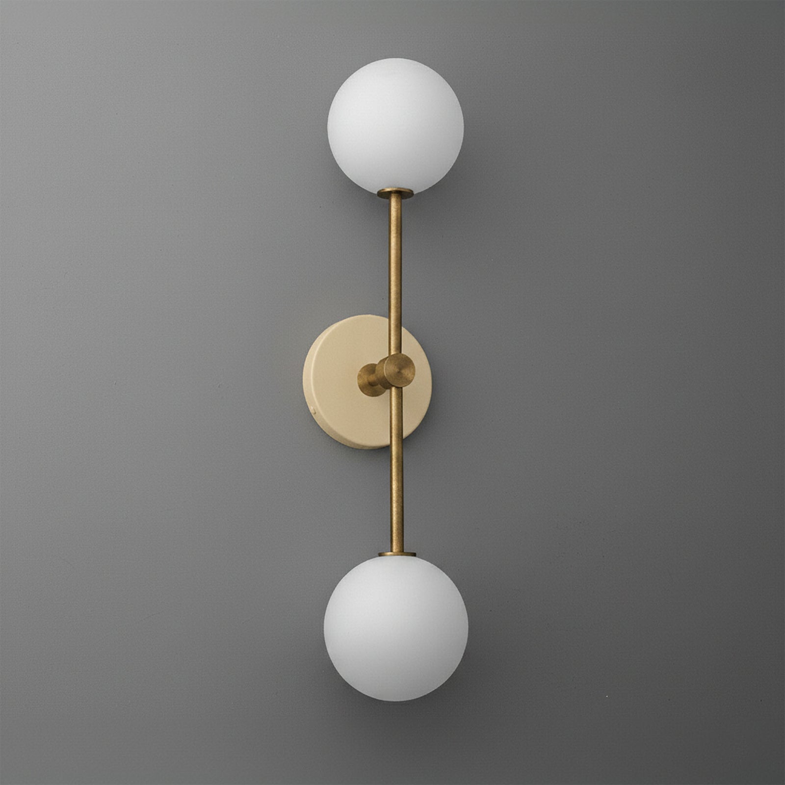 Wall sconce with raw brass finish and two round white frosted glass globes on vertical rod. - SCONCE MODEL NO. 9776