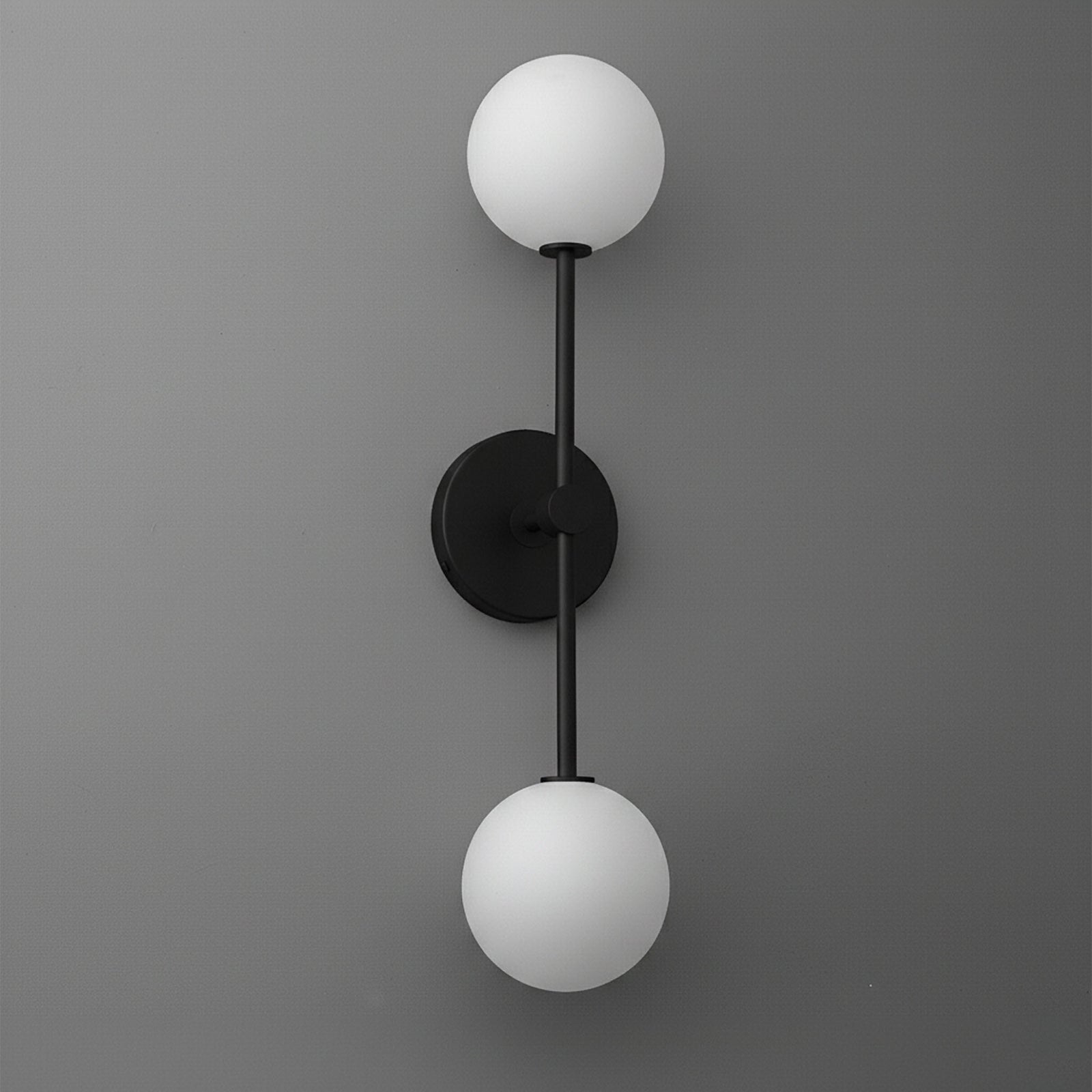 Black metal sconce with two frosted white glass globe shades on a gray wall. - SCONCE MODEL NO. 9776