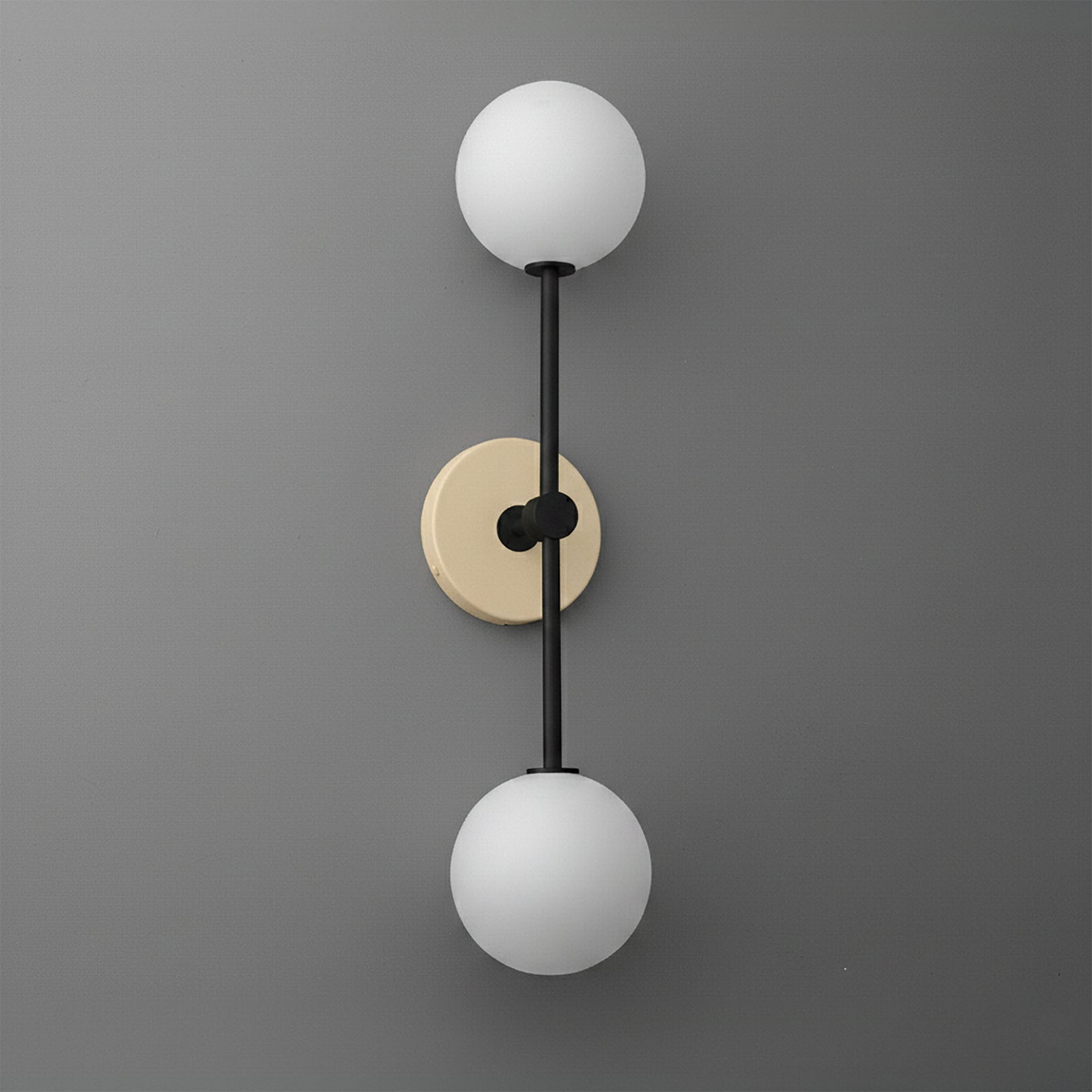 Double globe wall sconce with raw brass circular backplate and black vertical rod. - SCONCE MODEL NO. 9776