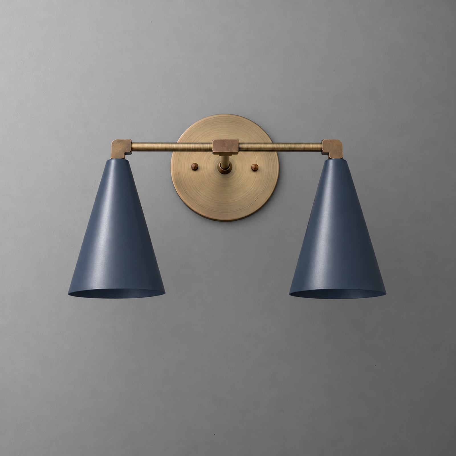 Two-light vanity light in Antique Brass with Coal Blue cone shades on a straight arm and a round wall plate. - VANITY LIGHT MODEL NO. 1184