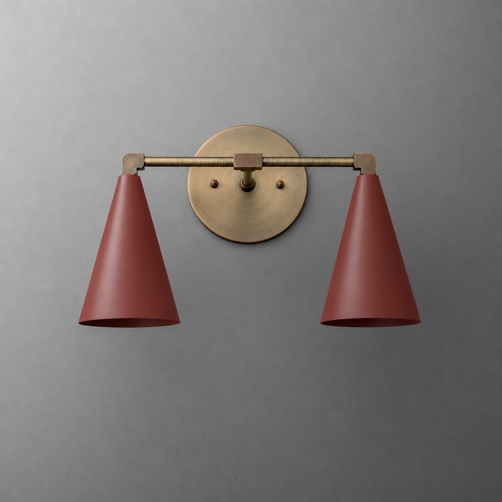Two-light vanity light in Antique Brass with Brick Red cone shades on a straight arm and a round wall plate. - VANITY LIGHT MODEL NO. 1184