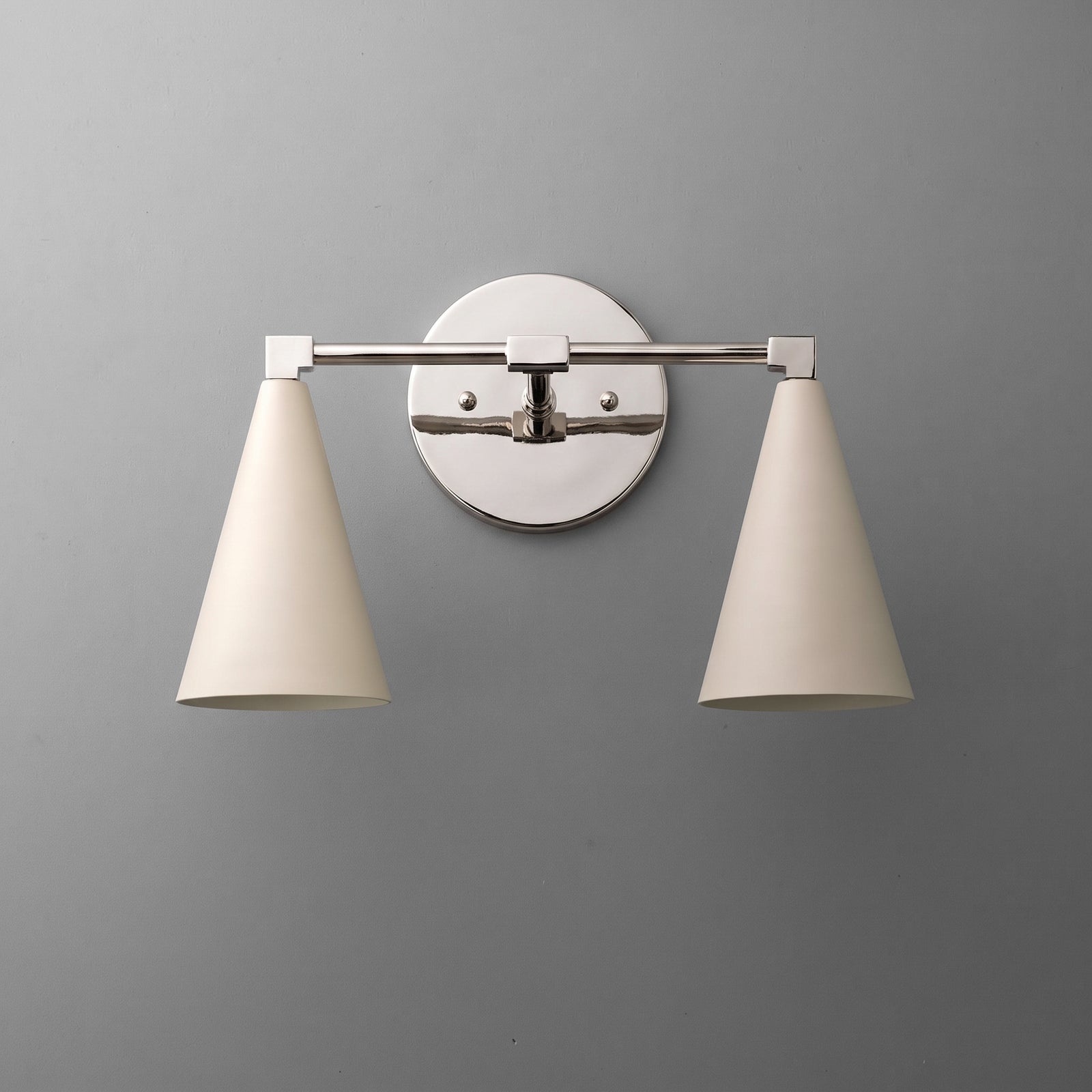 Two-light vanity light in Polished Nickel with Cream cone shades on a straight arm and a round wall plate. - VANITY LIGHT MODEL NO. 1184
