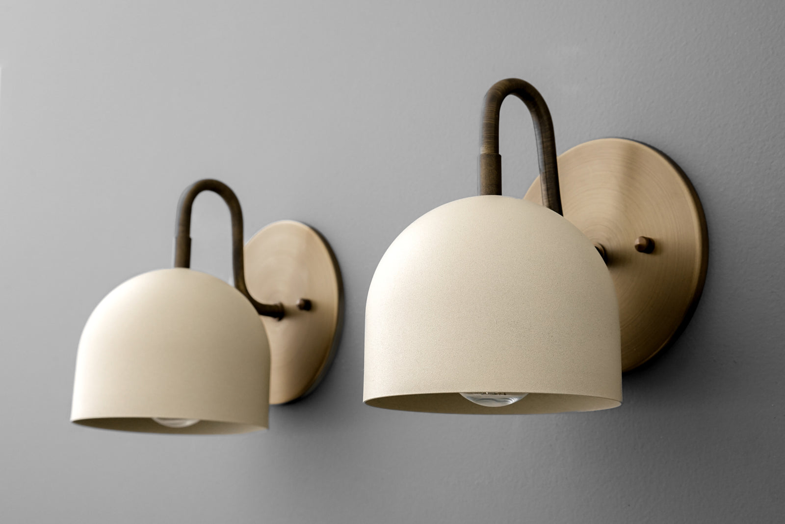 Antique brass wall sconce with curved arm and smooth cream dome-shaped shade. - Sconce Model No. 5416