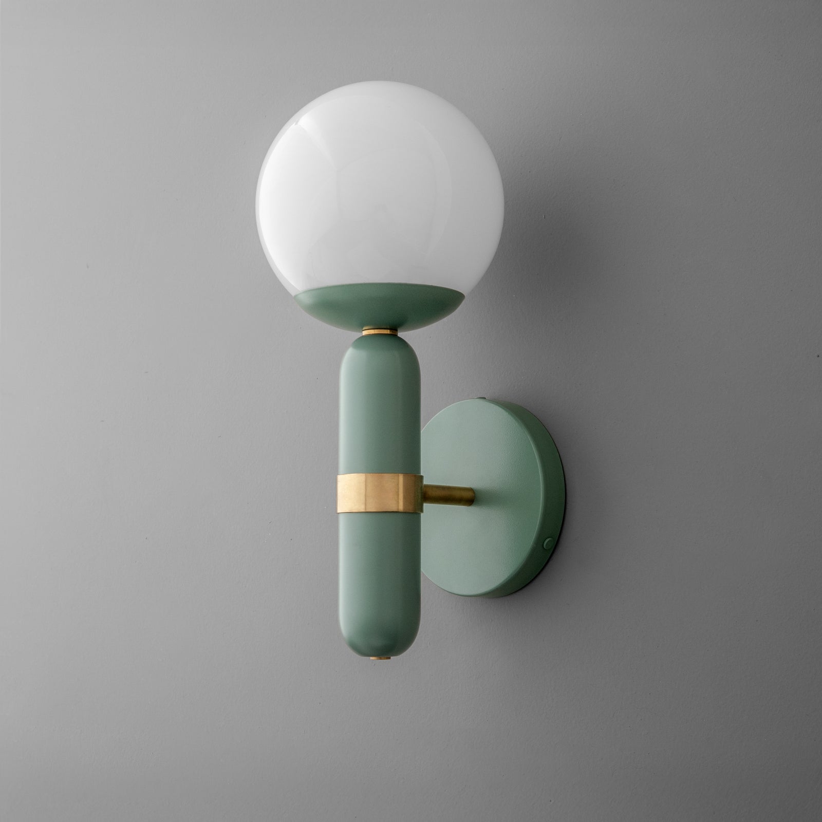 Wall sconce with raw brass accent and green cylindrical base holding white globe shade on gray wall. - SCONCE MODEL NO. 4786