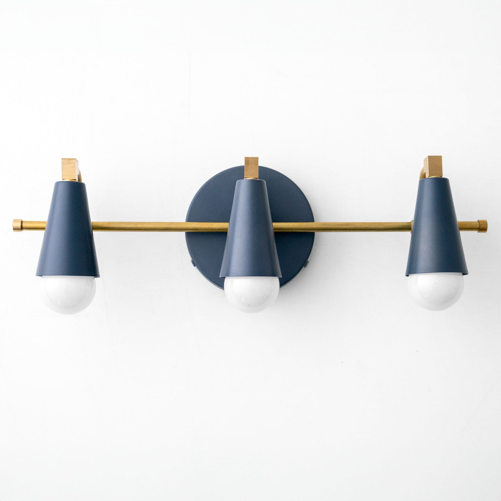 Three-bulb vanity light with coal blue conical shades and raw brass accents on horizontal bar. - VANITY LIGHT MODEL NO. 8084