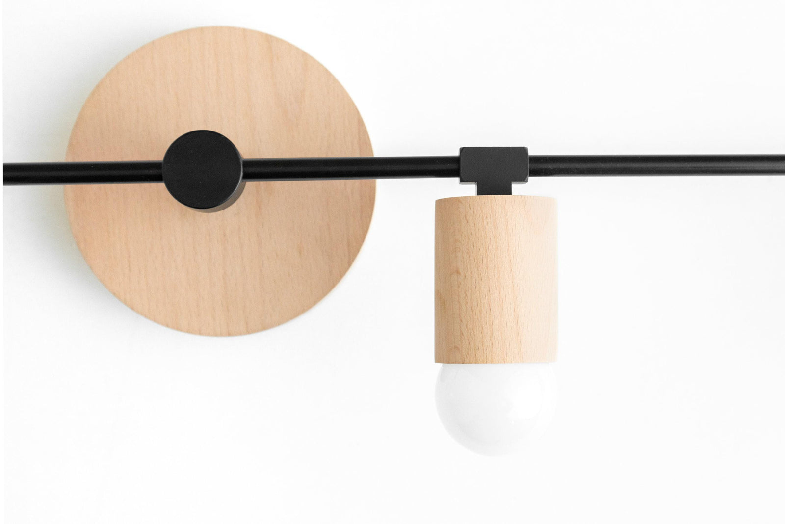 Minimalist vanity light with natural wood circular backplate, black metal rod, and exposed bulb suspended in light wood. - VANITY LIGHT MODEL NO. 2017