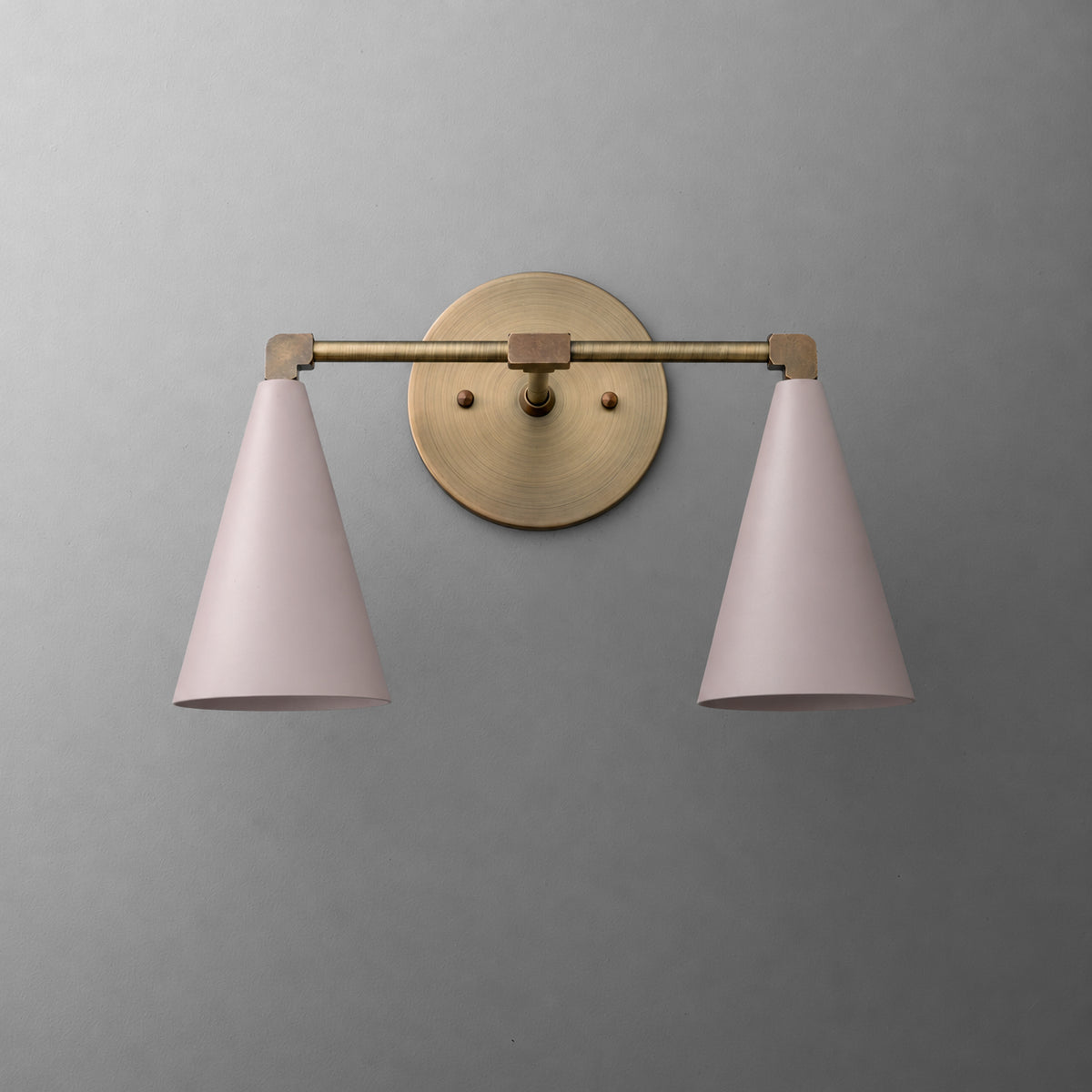 Two-light vanity light in Antique Brass with Mauve cone shades on a straight arm and a round wall plate. - VANITY LIGHT MODEL NO. 1184