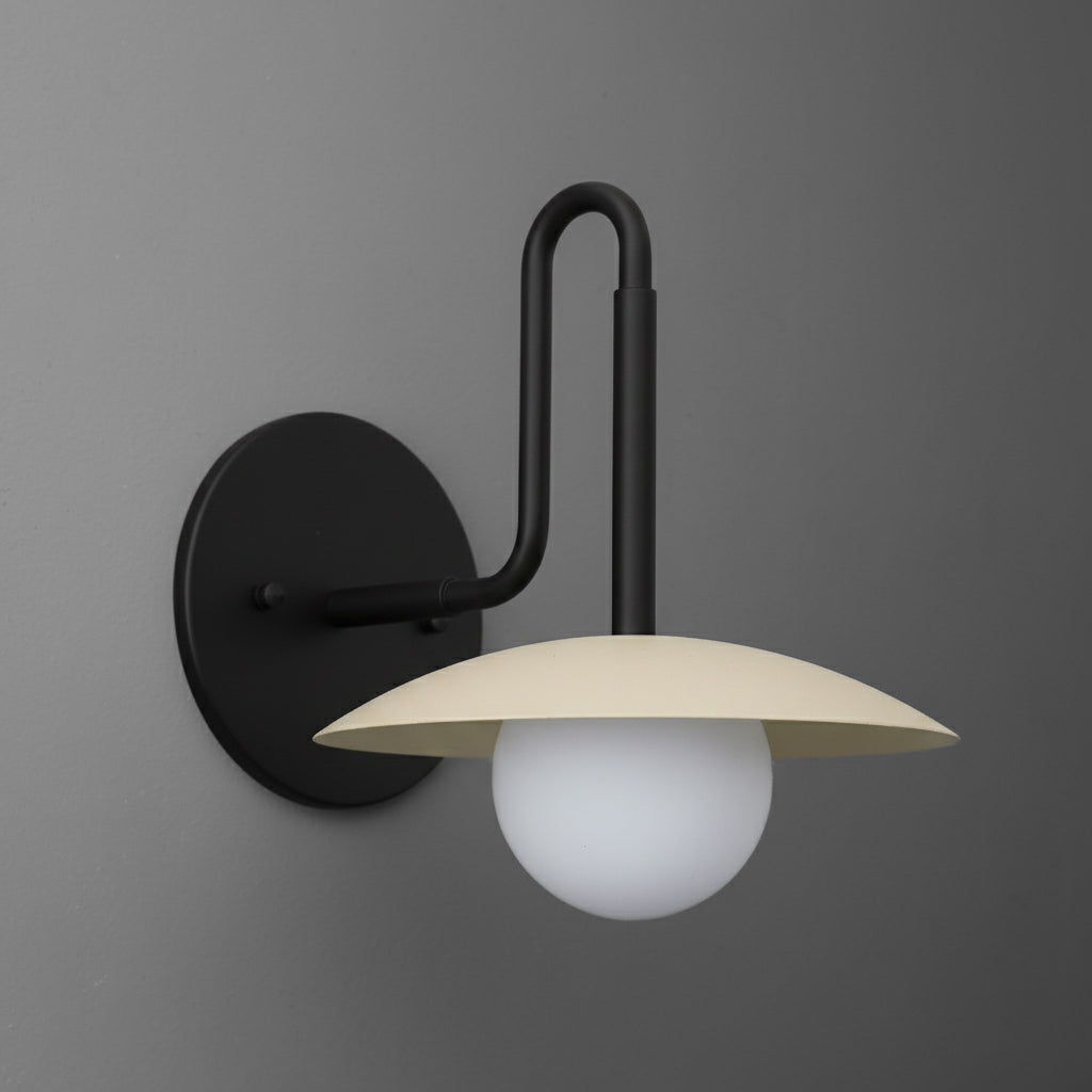 Black metal wall sconce with curved arm, beige flat dome shade, and frosted glass globe bulb. - SCONCE MODEL NO. 1017