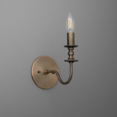 Antique brass wall sconce with curved arm and candle-style bulb holder. - SCONCE MODEL NO. 9915