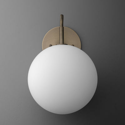 Minimalist wall sconce with frosted white globe and antique brass mount on gray background. - SCONCE MODEL NO. 0478