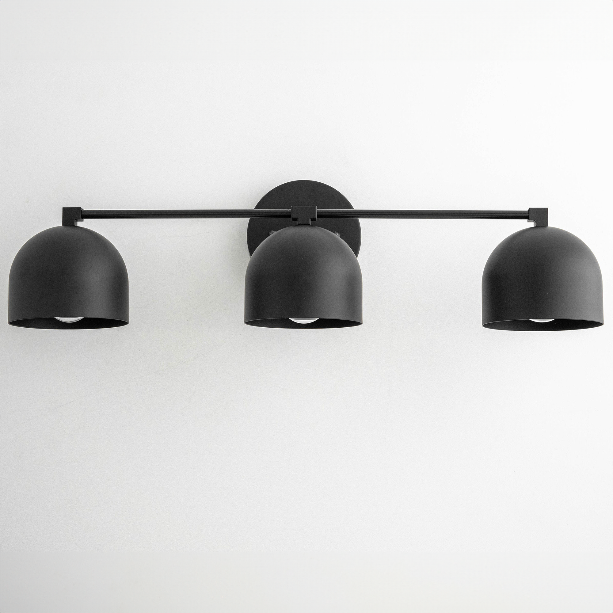 Black mid-century modern three-light vanity fixture with dome-shaped metal shades and horizontal bar mount. - VANITY LIGHT MODEL NO. 7565
