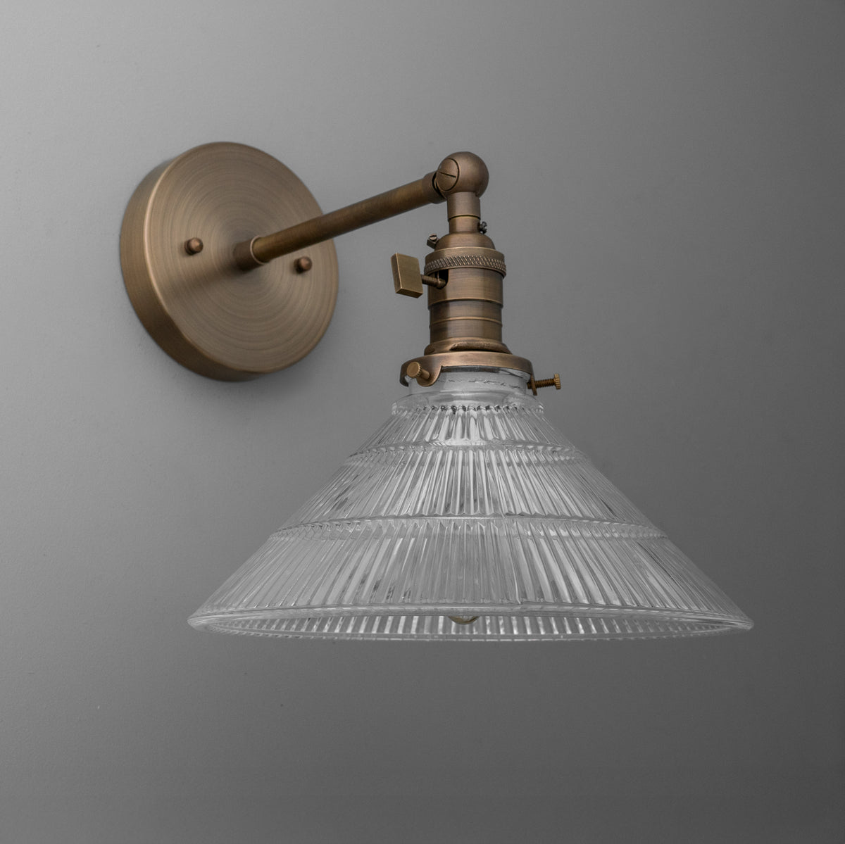 Wall-mounted bronze sconce with ribbed clear glass conical shade and adjustable arm. - SCONCE MODEL NO. 3170