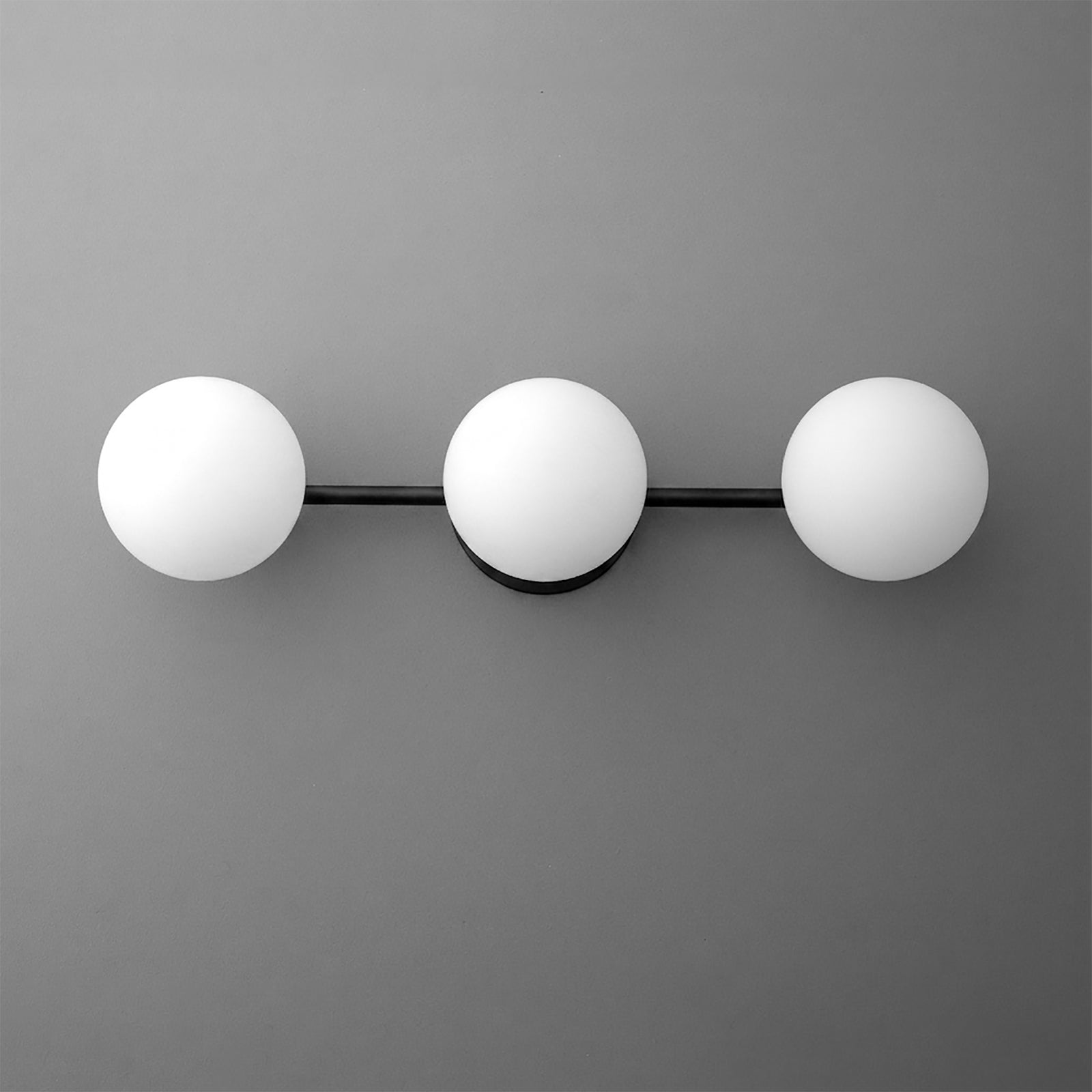 Black metal vanity light with three round white frosted glass bulbs evenly spaced on a horizontal bar. - VANITY LIGHT MODEL NO. 9250