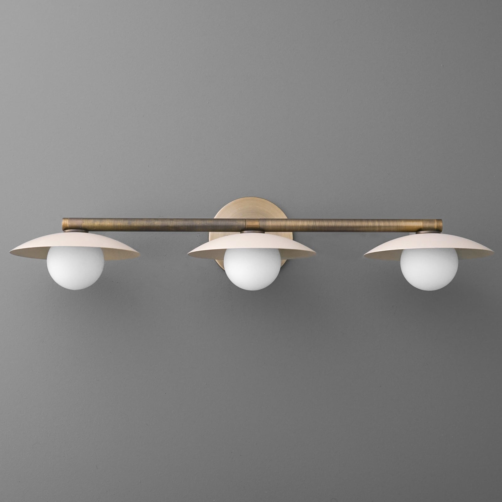 Three-bulb vanity light with round white glass shades and brushed brass horizontal bar mount. - VANITY LIGHT MODEL NO. 1156