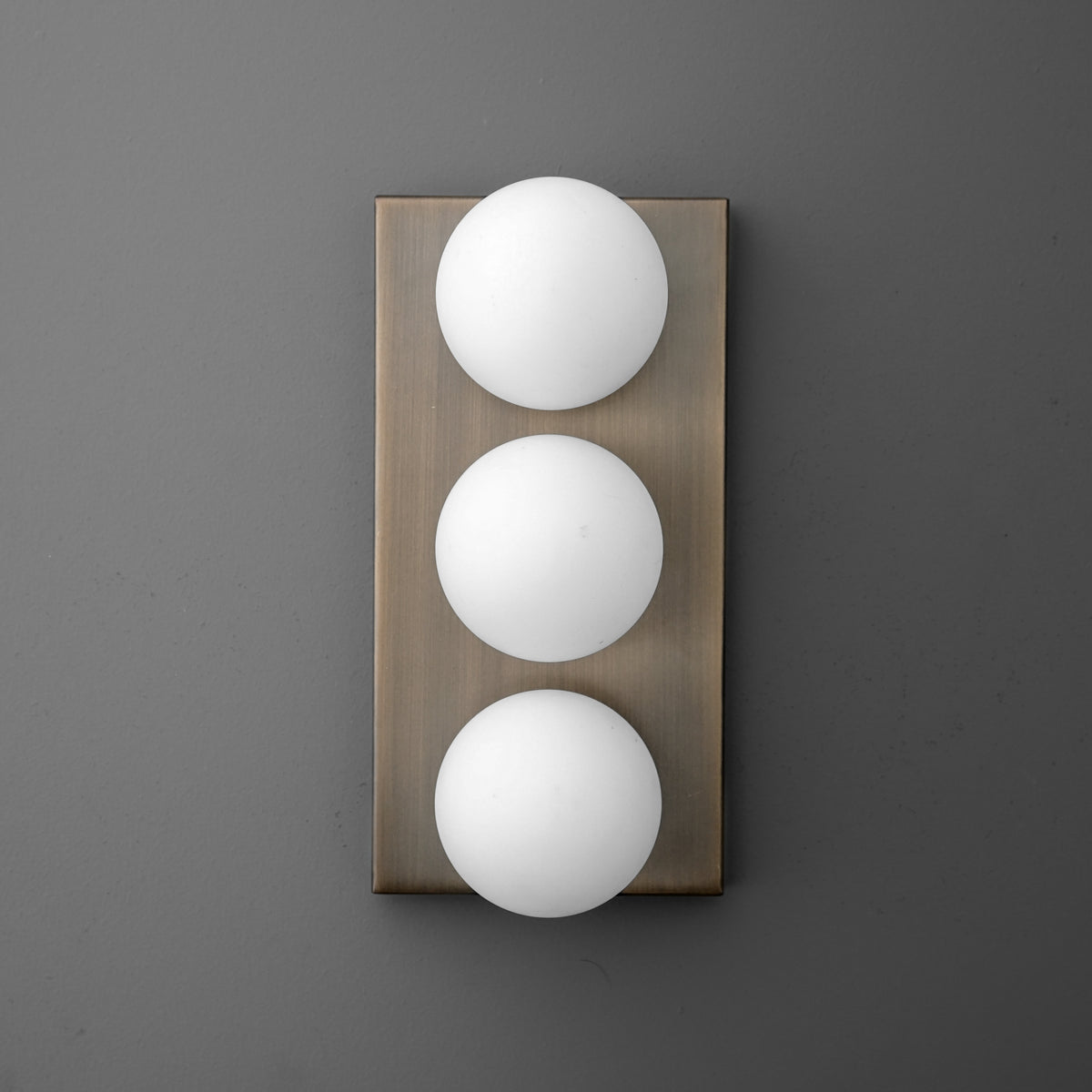 Wall sconce with three round white glass globes mounted vertically on a rectangular bronze backplate. - SCONCE MODEL NO. 2623