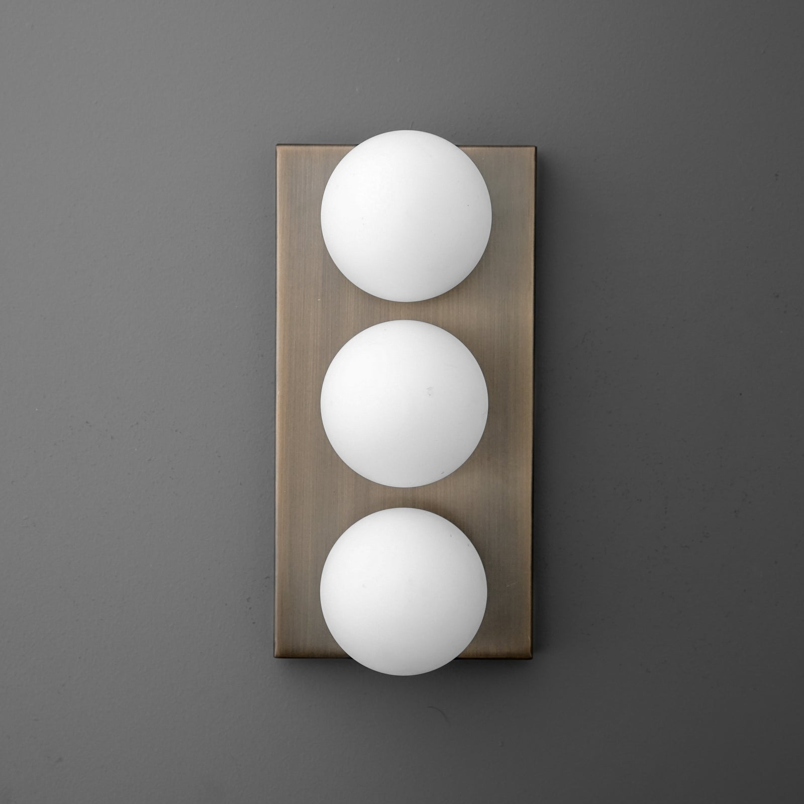 Wall sconce with three round white glass globes mounted vertically on a rectangular bronze backplate. - SCONCE MODEL NO. 2623