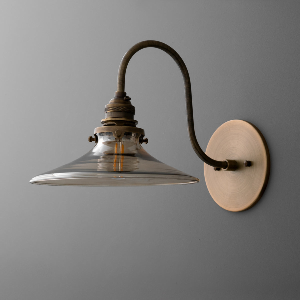 Wall-mounted single-bulb sconce with curved bronze arm and wide clear glass shade. - SCONCE MODEL NO. 3901