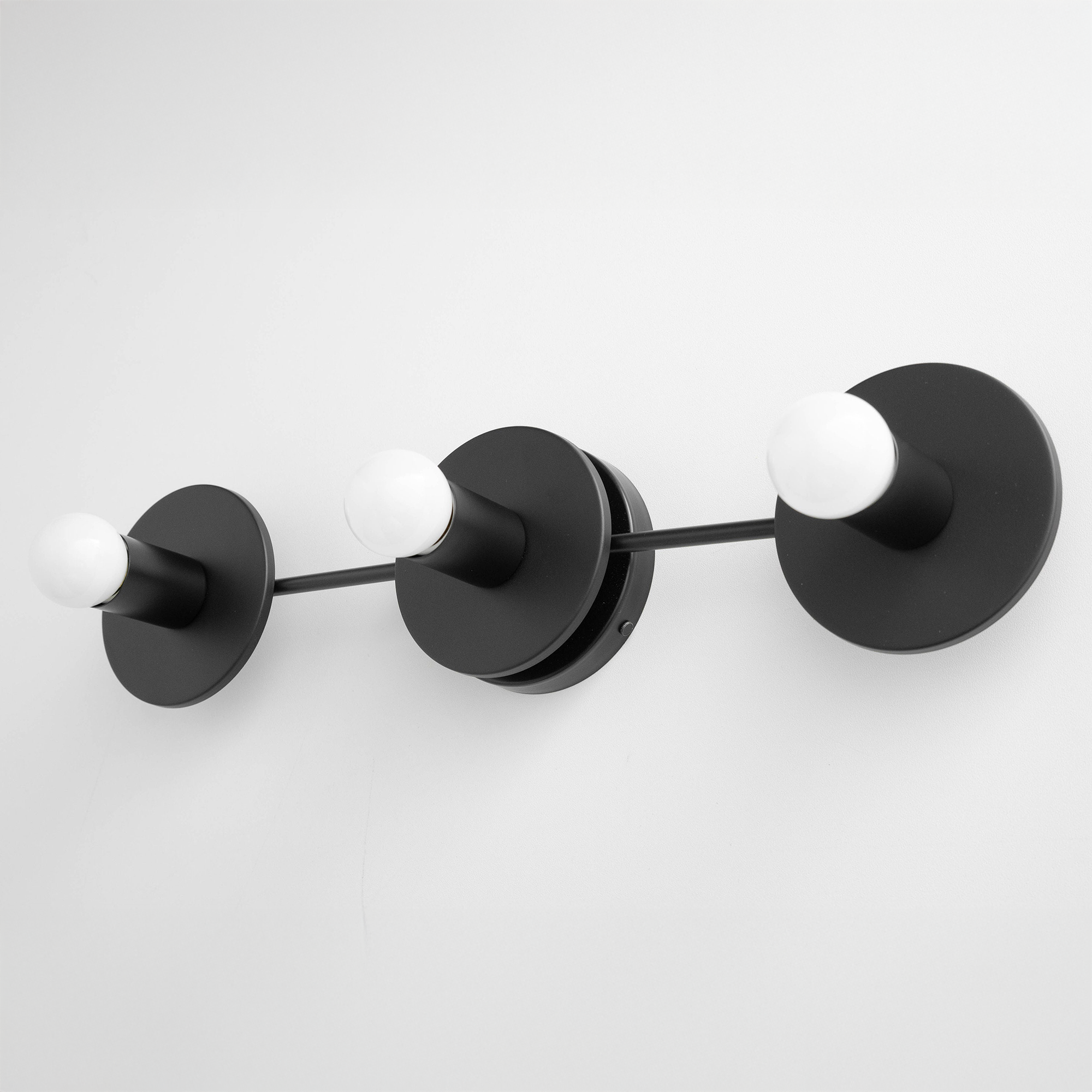 Black mid-century modern vanity light with three exposed round bulbs and circular wall mounts. - VANITY LIGHT MODEL NO. 5708