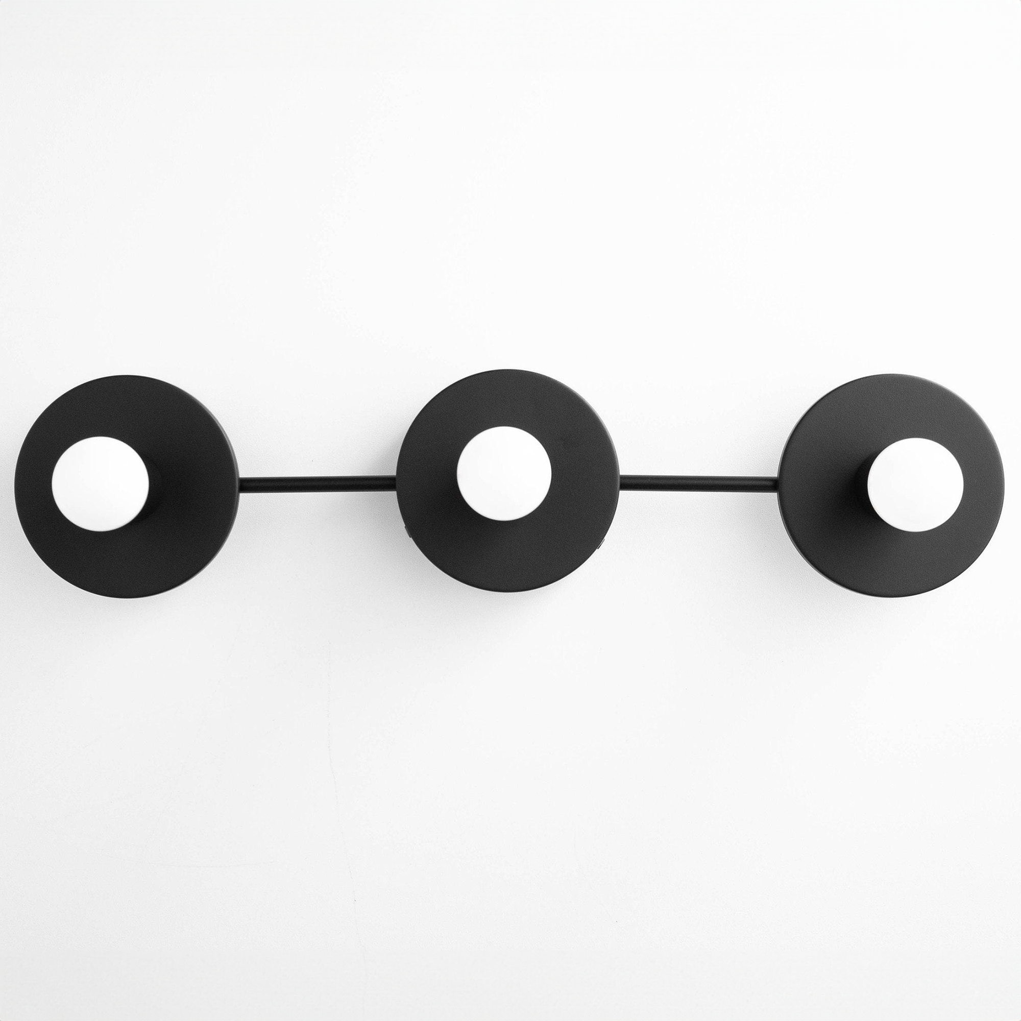 Black mid-century modern vanity light with three circular, bare bulb fixtures mounted on a horizontal bar. - VANITY LIGHT MODEL NO. 5708