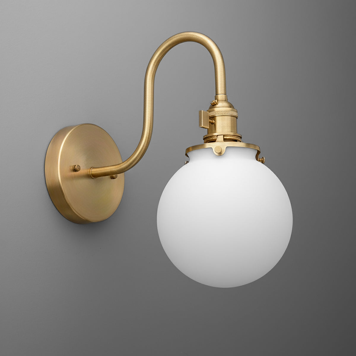 Wall sconce with matte brass curved arm and round white glass globe shade. - SCONCE MODEL NO. 0017