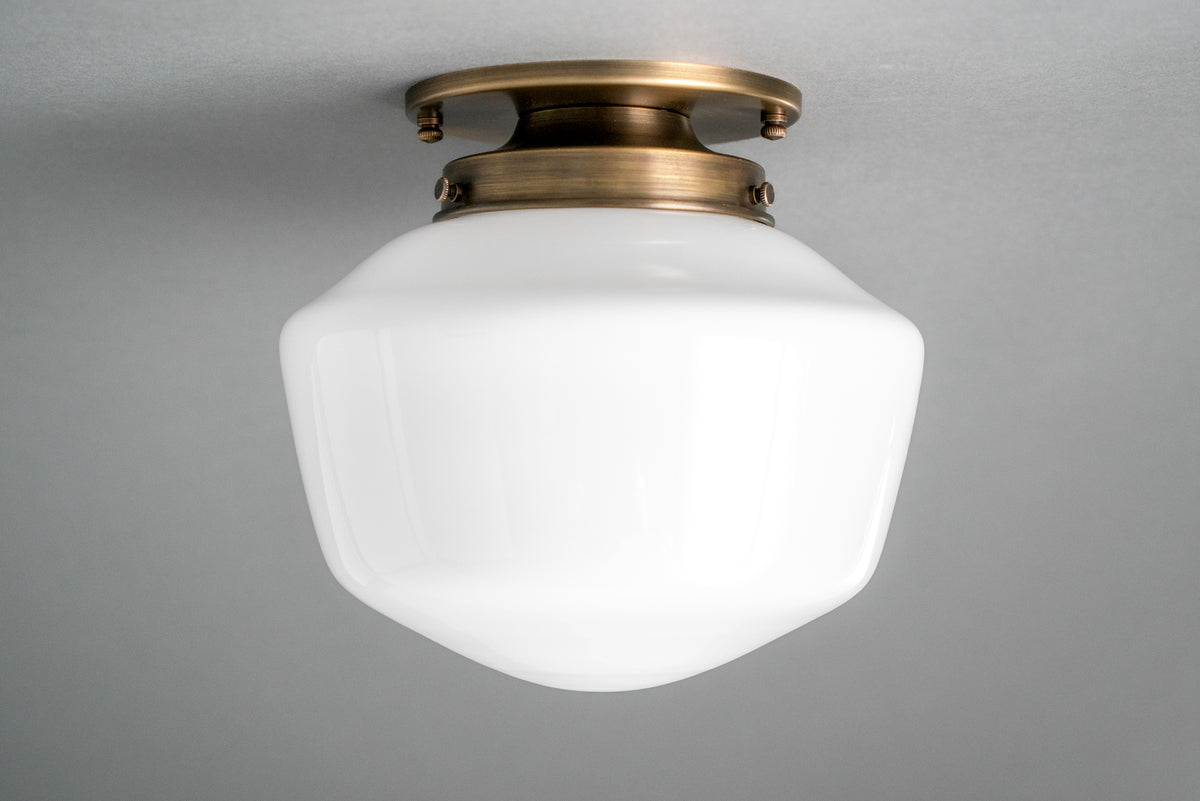 Flush mount ceiling light in Antique Brass holding an opal glass schoolhouse shade. - CEILING LIGHT MODEL NO. 7149