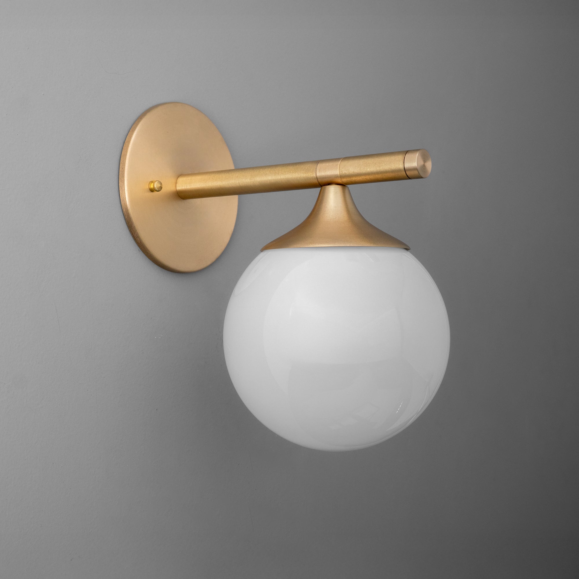Wall sconce with round white glass globe shade and matte brass horizontal arm and round base. - SCONCE MODEL NO. 1098