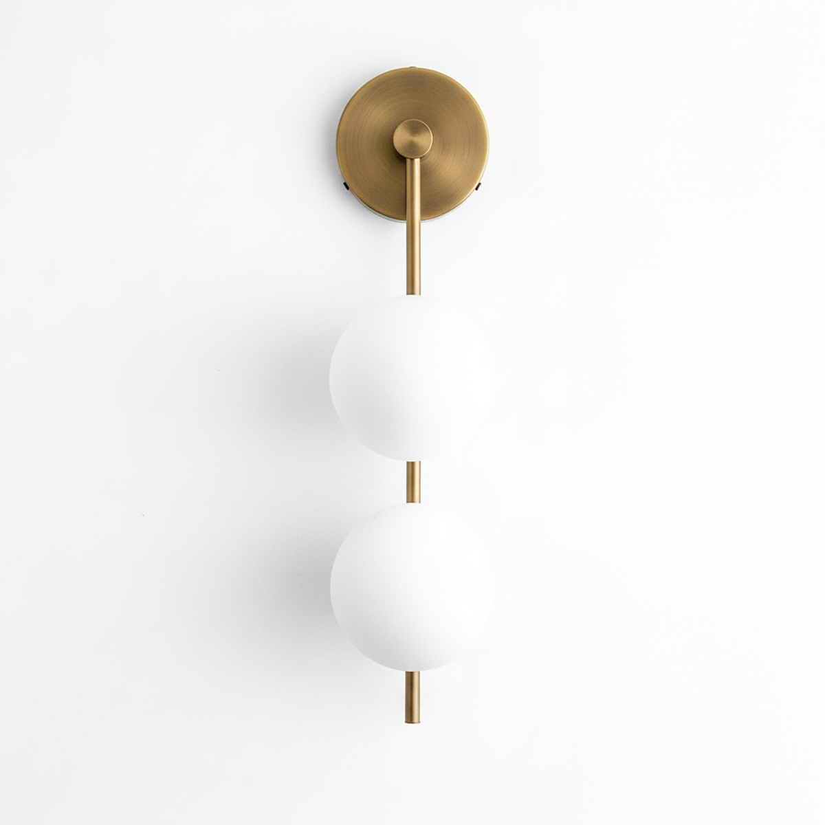 Wall-mounted sconce with two frosted white glass globes and antique brass finish on metal rod and round base. - SCONCE MODEL NO. 0344