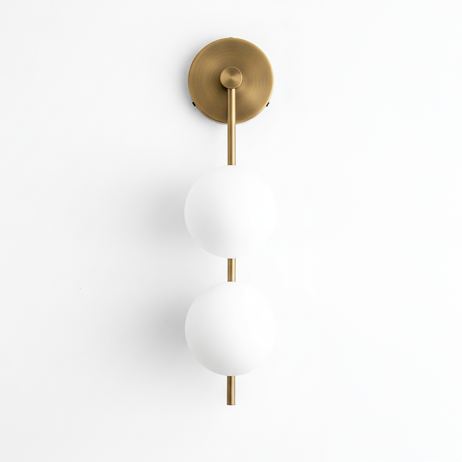 Wall-mounted sconce with two frosted white glass globes and antique brass finish on metal rod and round base. - SCONCE MODEL NO. 0344