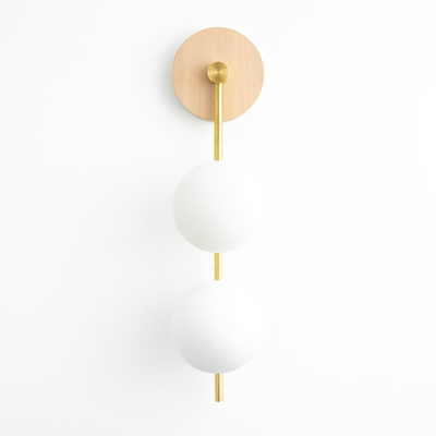 Wall sconce with natural wood round base, vertical brass rod, and two frosted white glass globe lights stacked vertically. - SCONCE MODEL NO. 0344