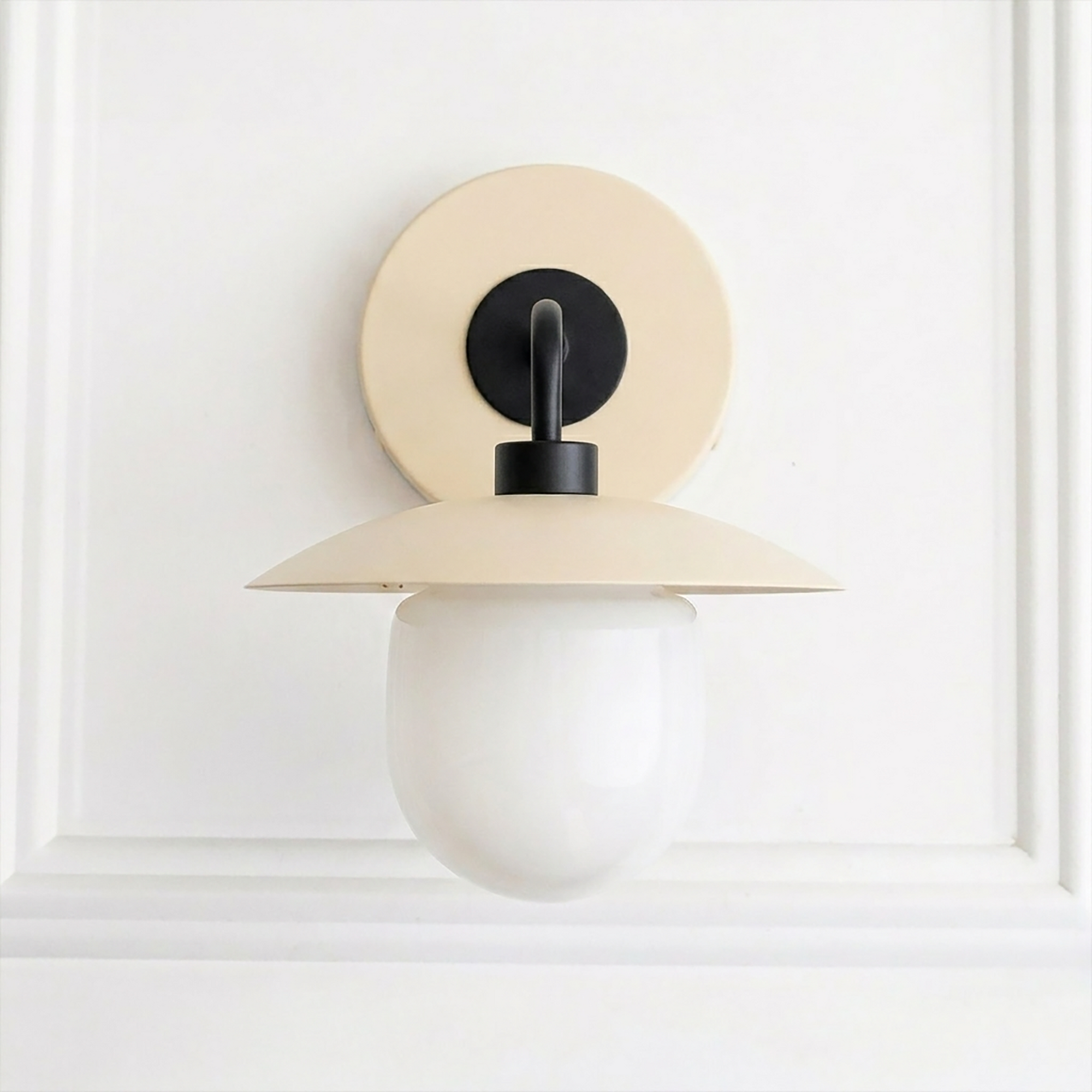 Mid-century modern cream metal sconce with round backplate and white globe bulb shade. - SCONCE MODEL NO. 7039