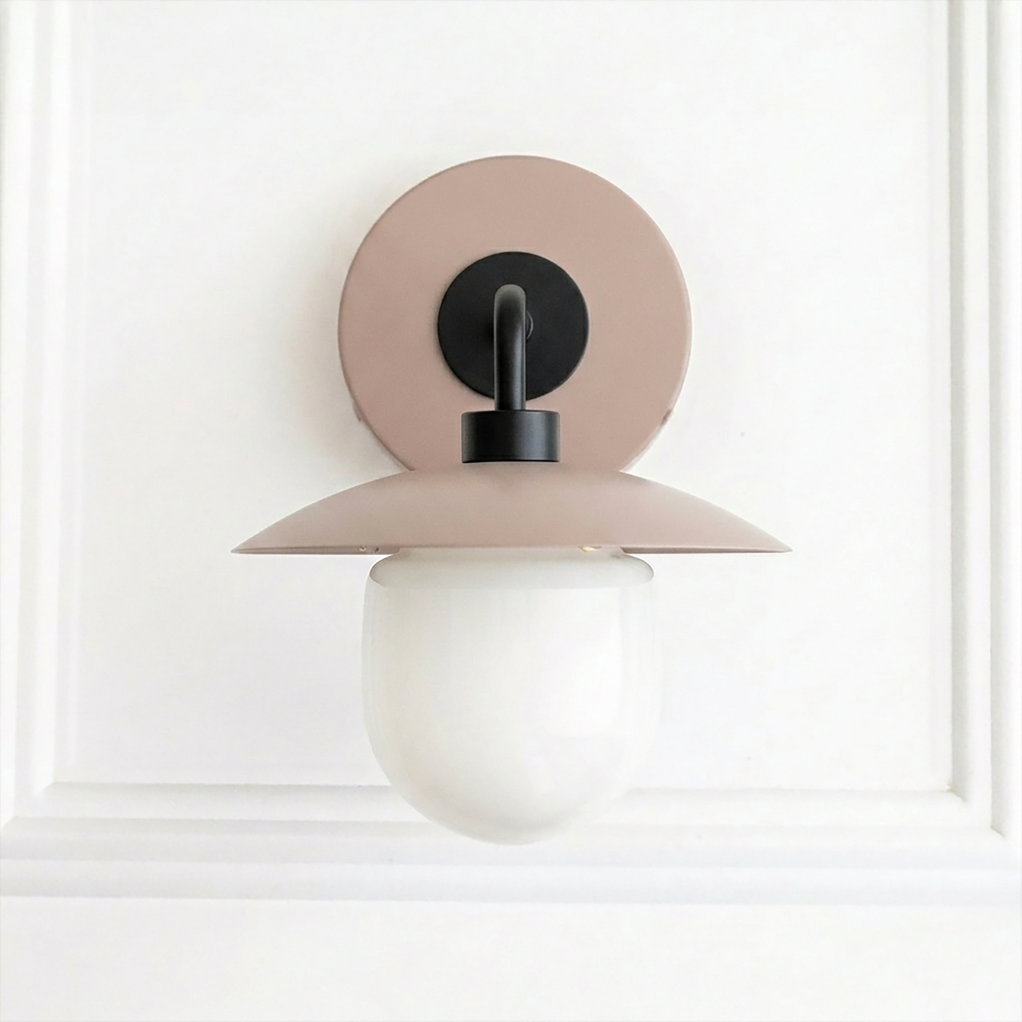Mid-century modern sconce with matte pink circular backplate, black metal arm, and frosted white globe shade. - SCONCE MODEL NO. 7039