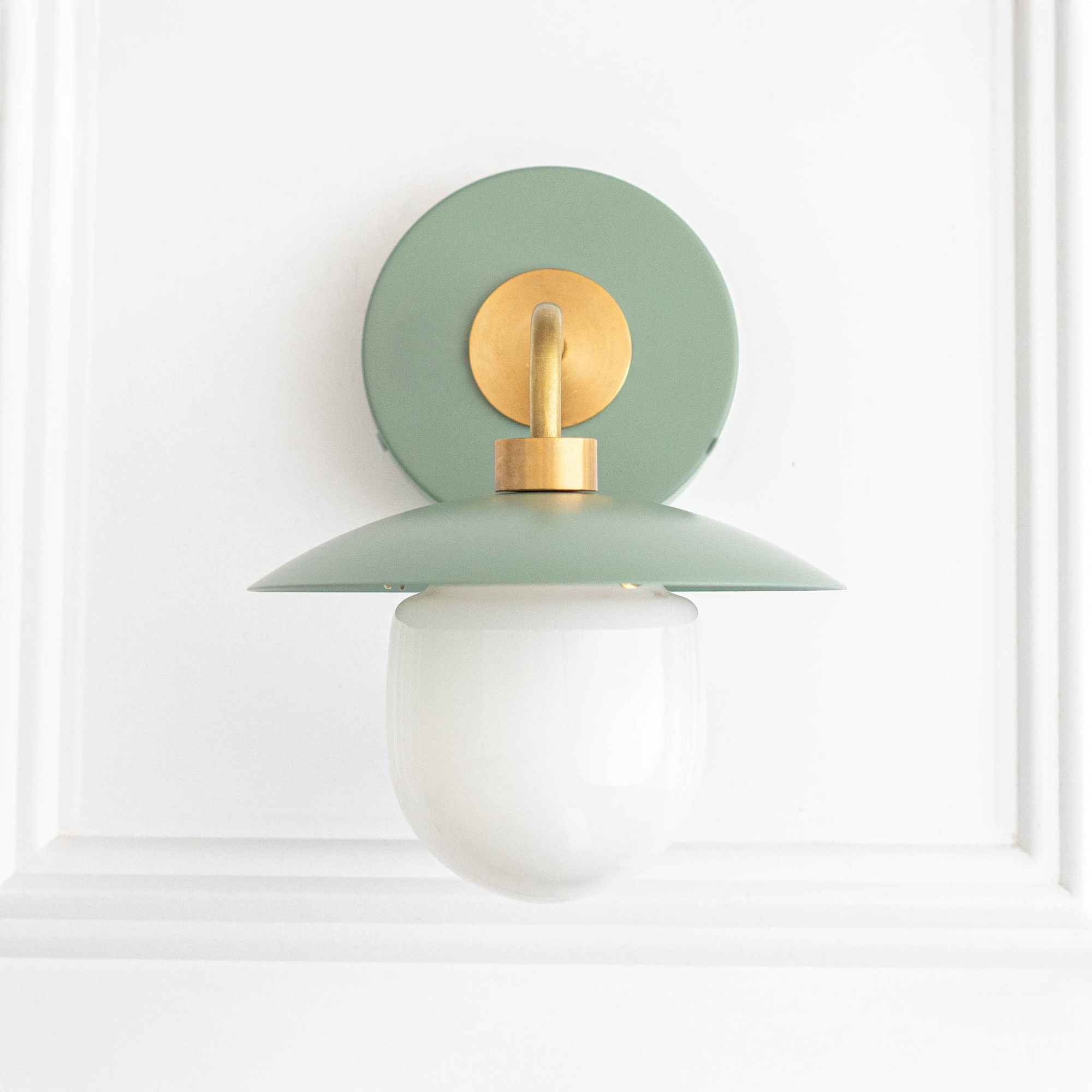 Mid-century modern wall sconce with matte green round backplate, brass arm, and white globe diffuser. - SCONCE MODEL NO. 7039