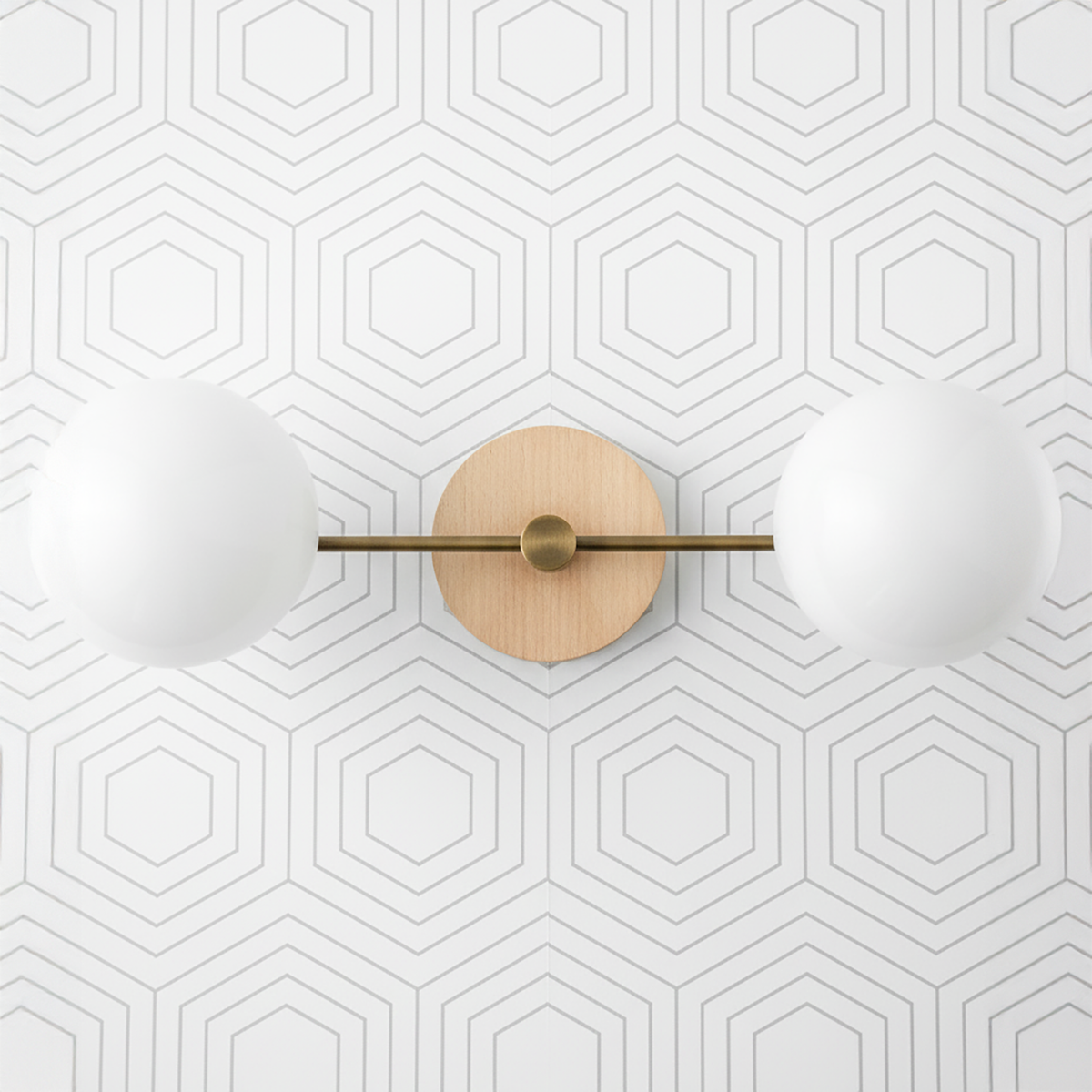 Two-globe vanity light with sealed brass finish and natural wood round backplate on geometric white wall. - VANITY LIGHT MODEL NO. 9474