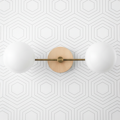 Two-globe vanity light with sealed brass finish and natural wood round backplate on geometric white wall. - VANITY LIGHT MODEL NO. 9474