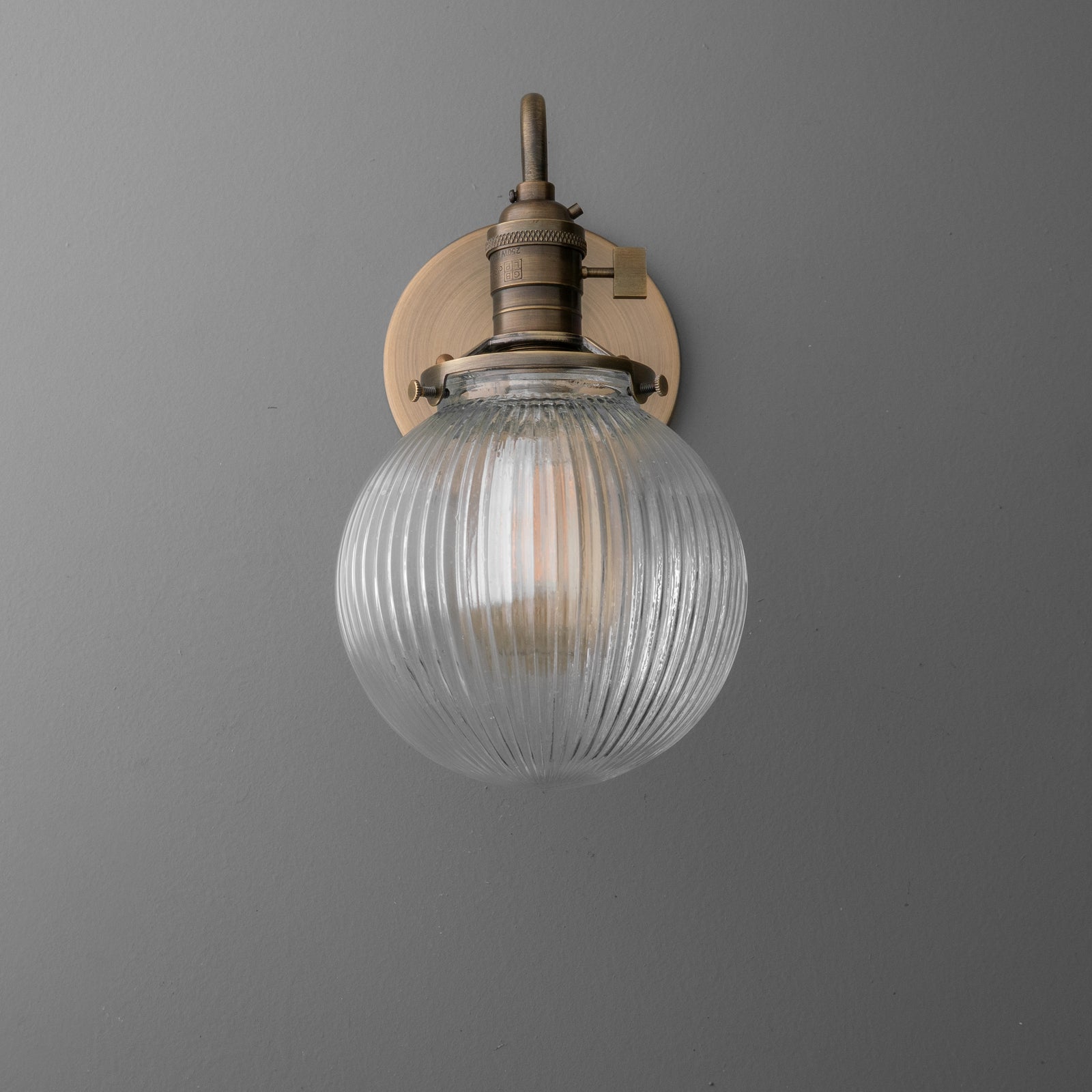 Wall-mounted antique brass sconce with ribbed glass globe shade and exposed bulb. - SCONCE MODEL NO. 3331