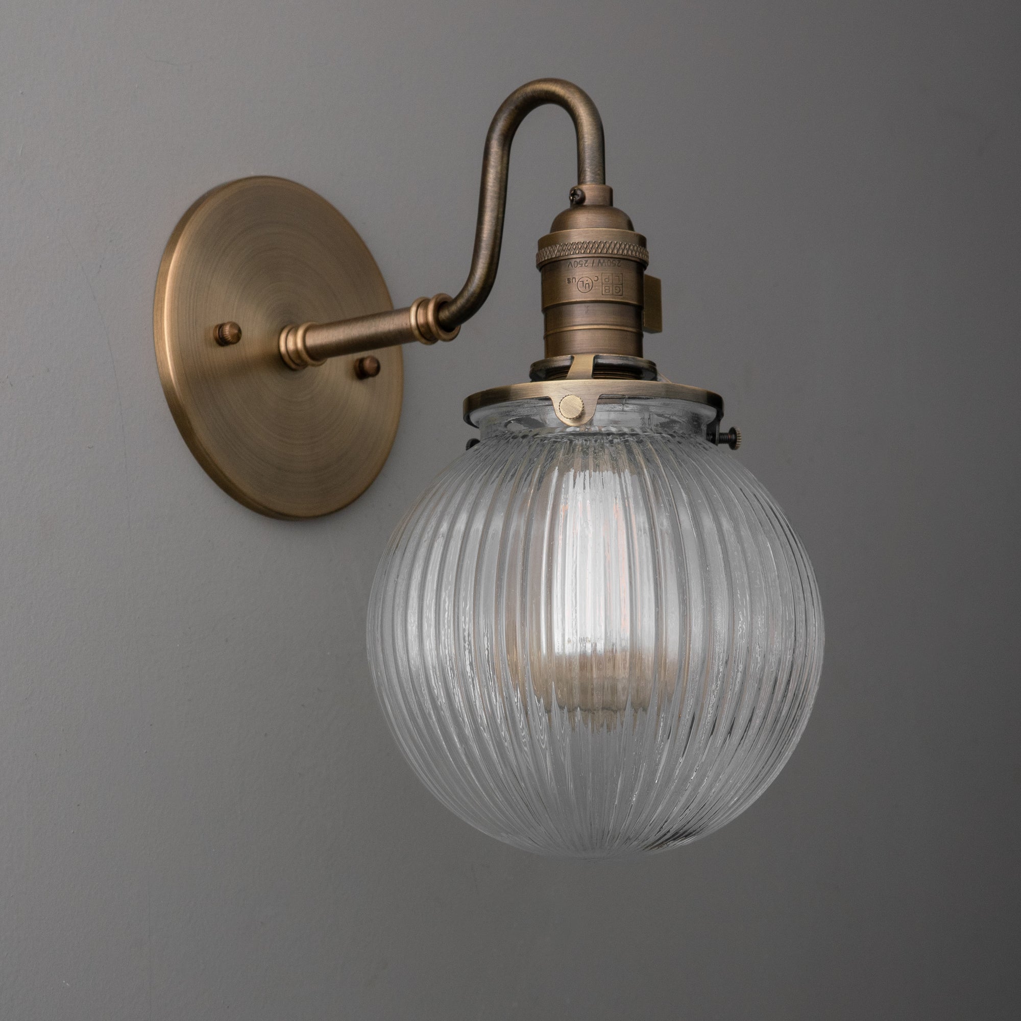 Antique brass wall sconce with ribbed clear glass globe shade and exposed bulb. - SCONCE MODEL NO. 3331