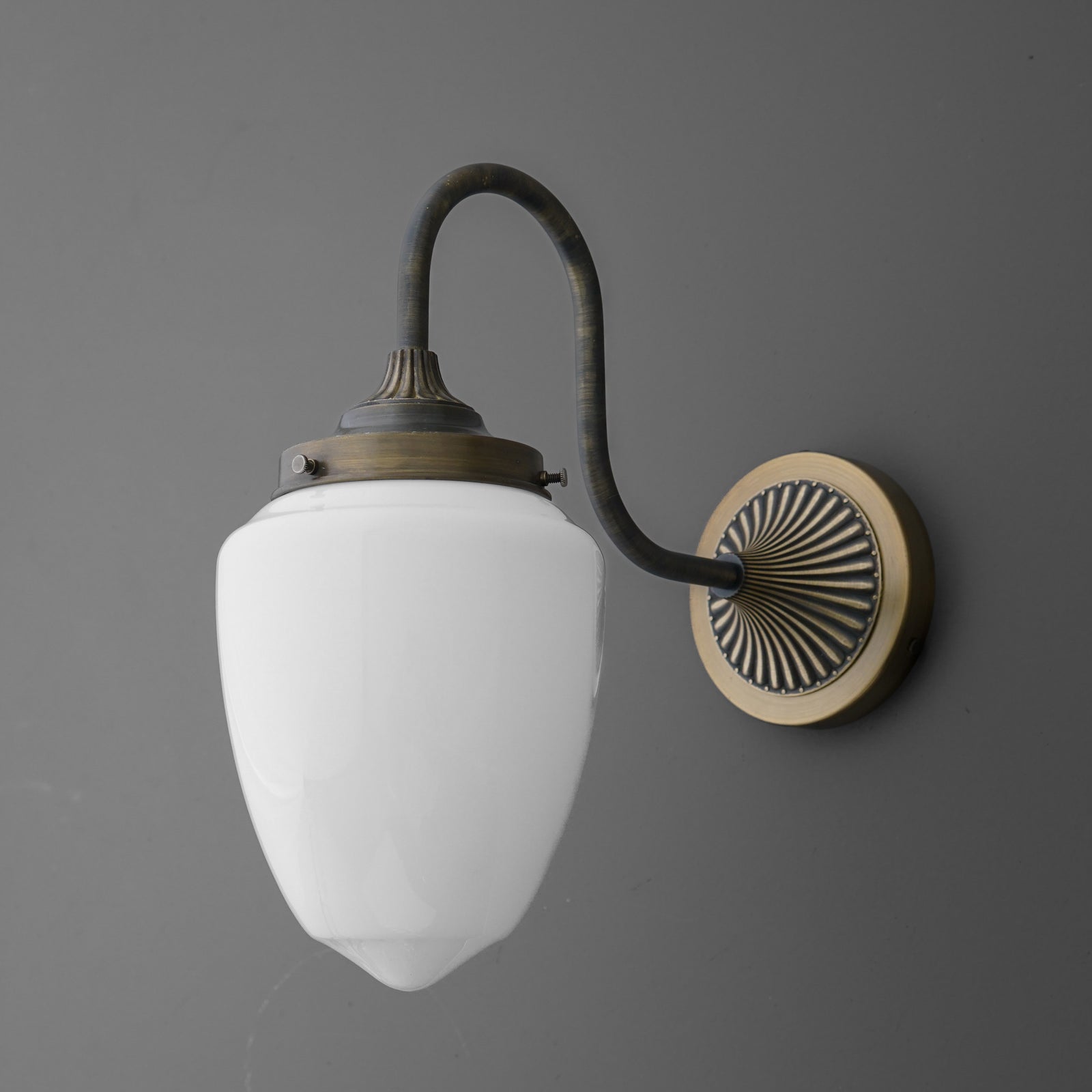 Wall sconce with curved bronze arm and round backplate, featuring white opal glass shade. - SCONCE MODEL NO. 1094