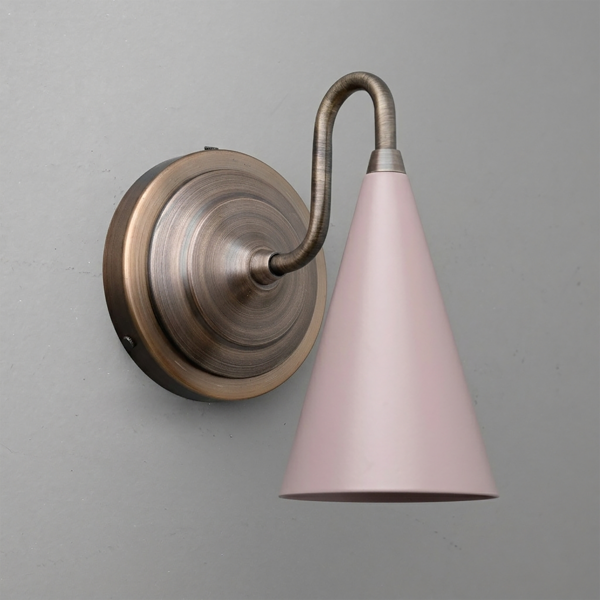 Wall sconce with curved antique brass arm and conical matte pink metal shade, up/down light design. - Sconce Model No. 6790