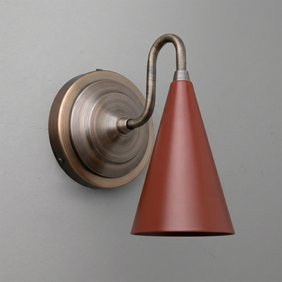Wall-mounted sconce with round bronze base and curved arm holding a matte rust-red cone-shaped shade. - Sconce Model No. 6790