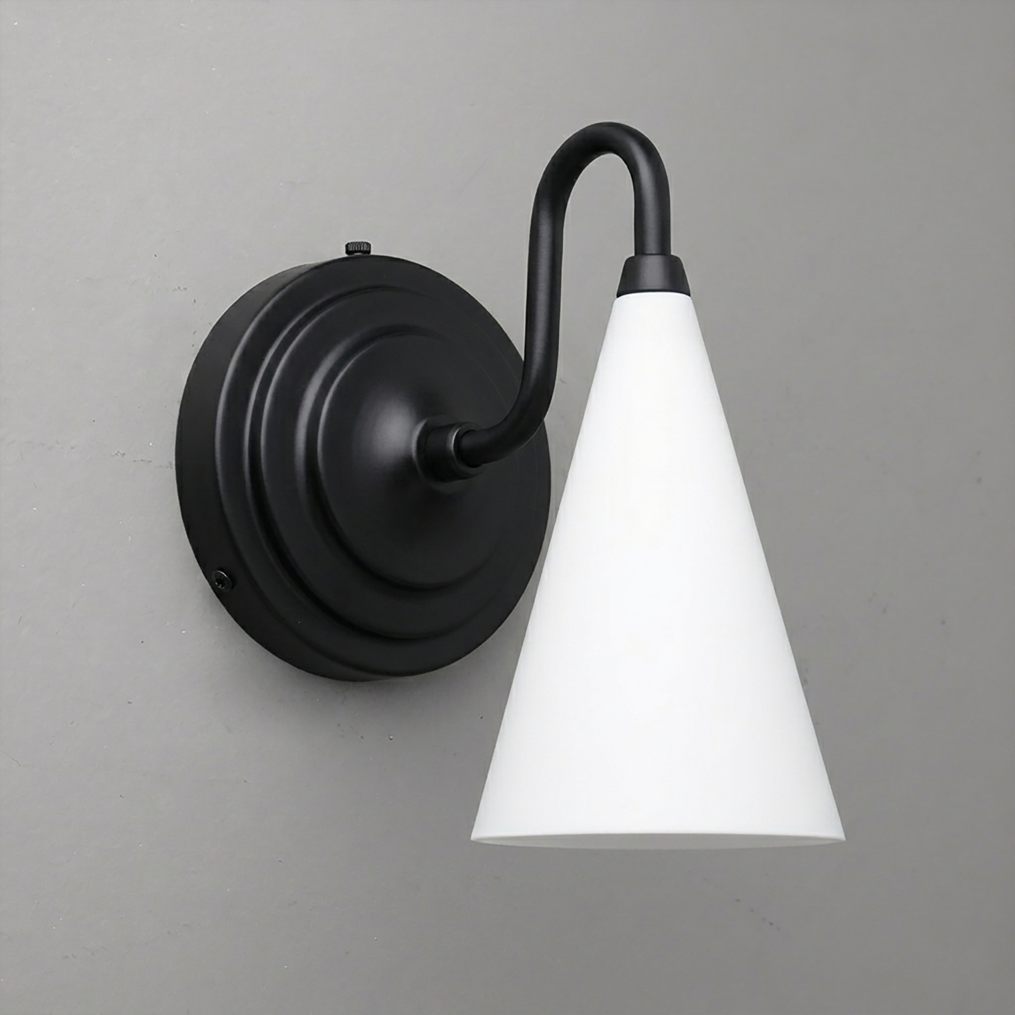 Black metal sconce with curved arm and white conical glass shade mounted on a round backplate. - Sconce Model No. 6790