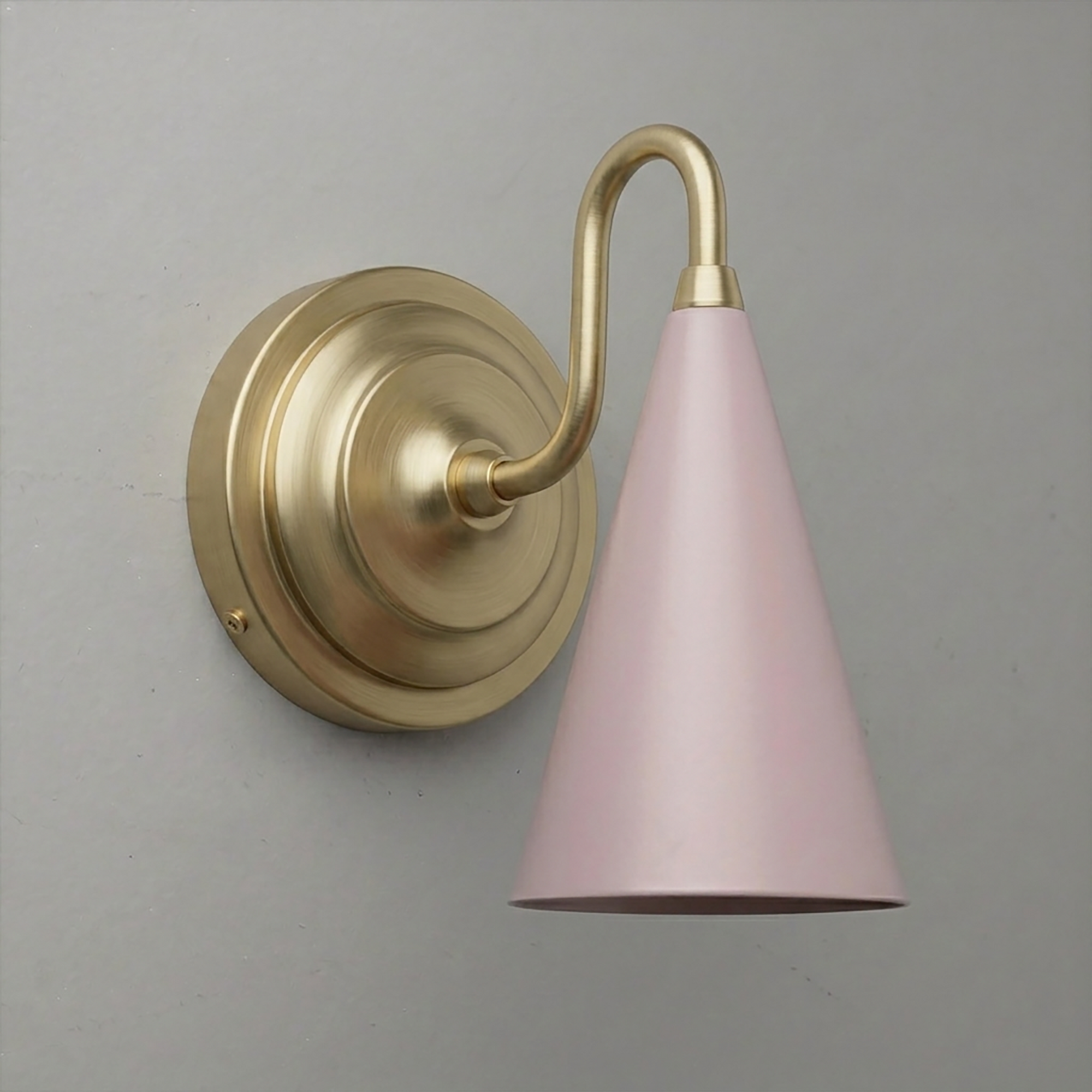 Gold-toned metal wall sconce with round backplate and pink conical shade facing downward. - Sconce Model No. 6790
