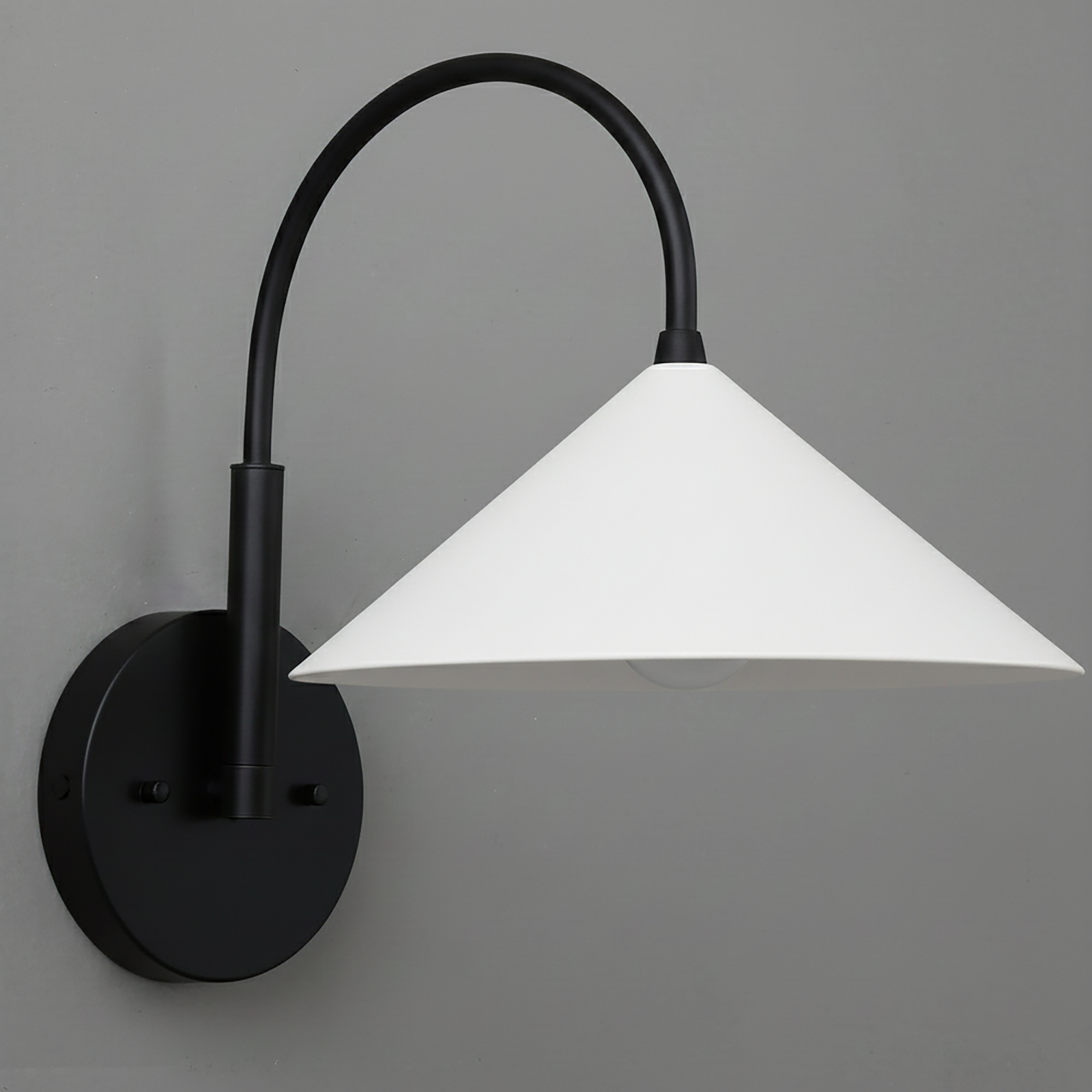 Black metal wall sconce with curved arm and white conical shade mounted on gray wall. - Sconce Model No. 1583
