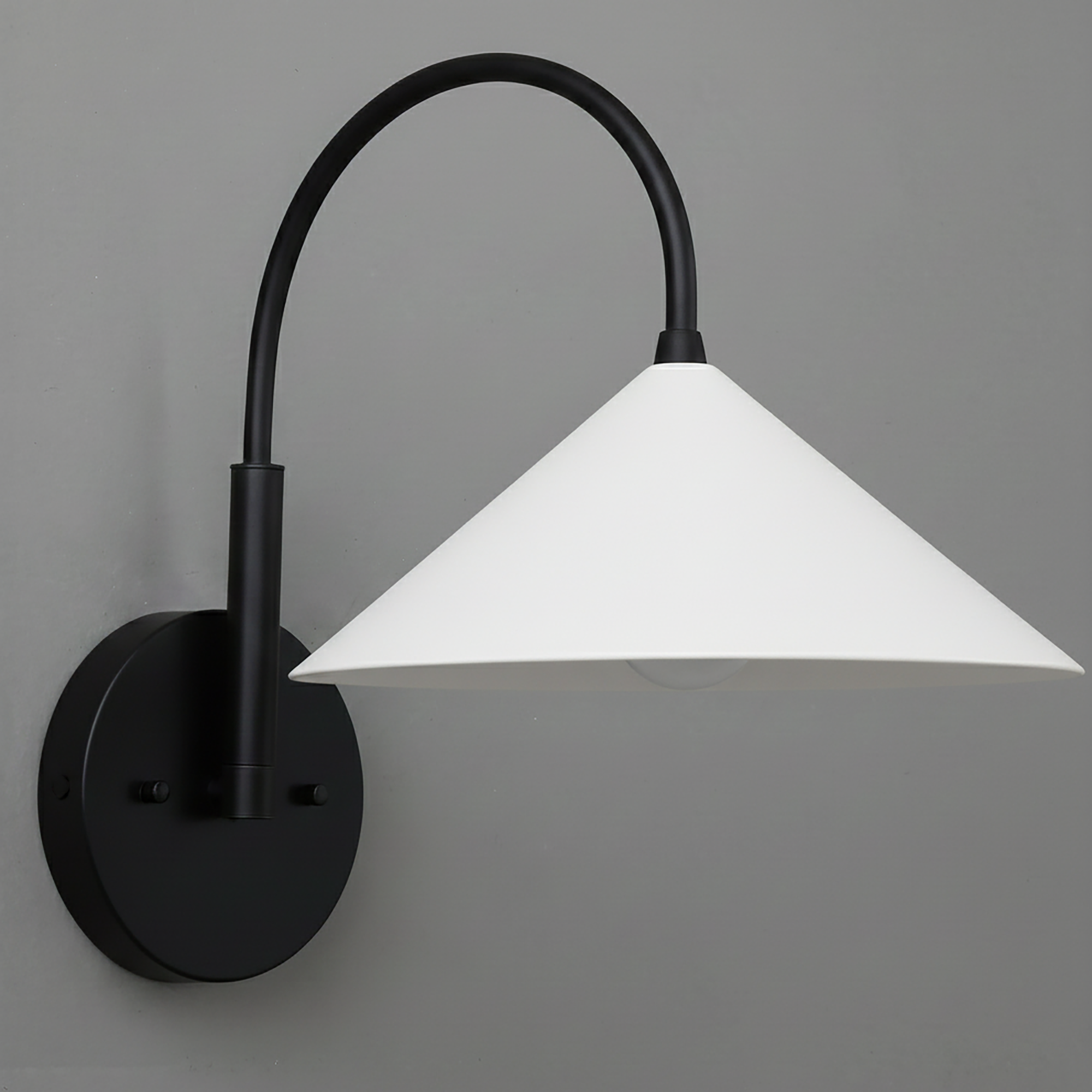 Black metal wall sconce with curved arm and white conical shade mounted on gray wall. - Sconce Model No. 1583